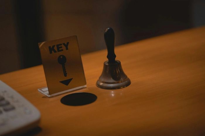 Chevalet « KEY » et sonnette de réception en laiton posés sur un comptoir en bois (photo Unsplash provisoire)