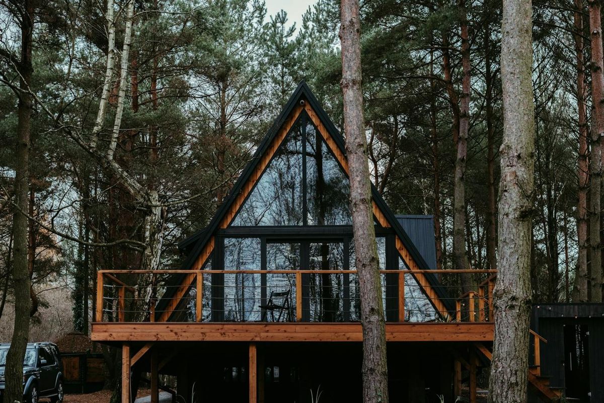 Chalet en A vitré avec terrasse en bois, niché dans une forêt de pins (photo Unsplash provisoire)