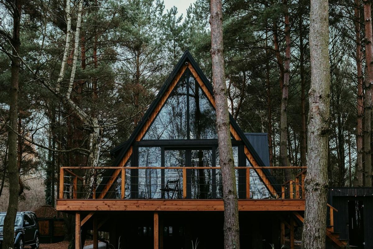 Chalet en A vitré avec terrasse en bois, niché dans une forêt de pins (photo Unsplash provisoire)