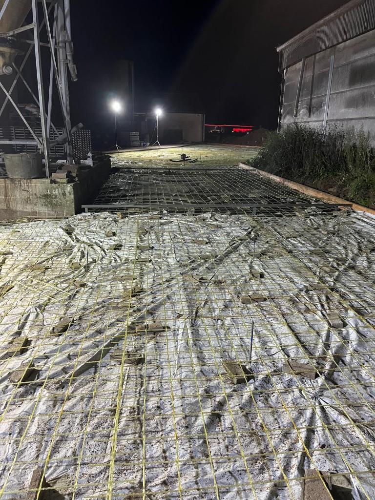 Glass-fibre mesh running the length of a barn slab, held up on spacers under work lights