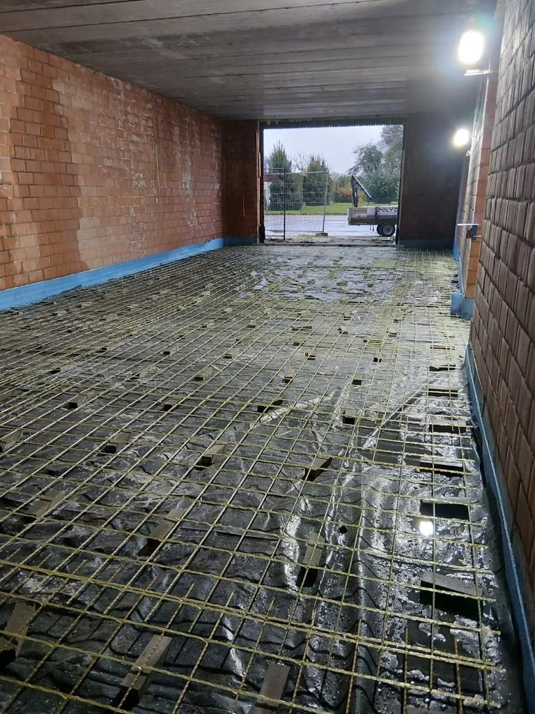 Residential garage floor prepared with glass-fibre mesh, blue edge strip and open doorway