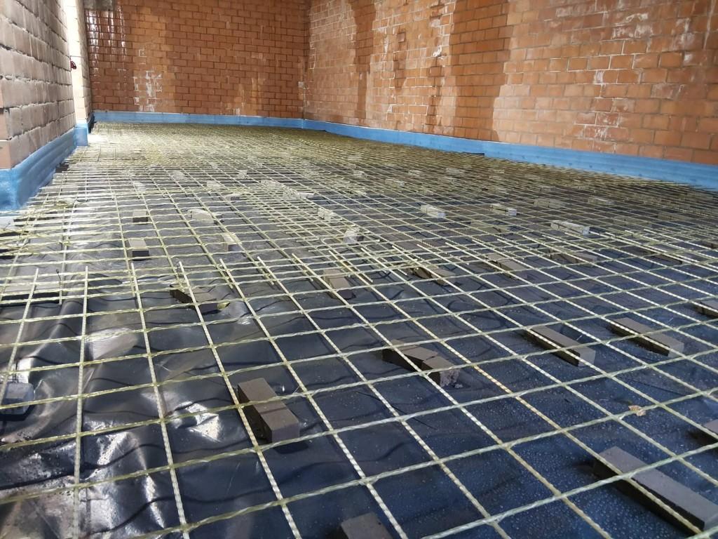 Overview of glass-fibre mesh laid across a residential floor slab with perimeter edge insulation