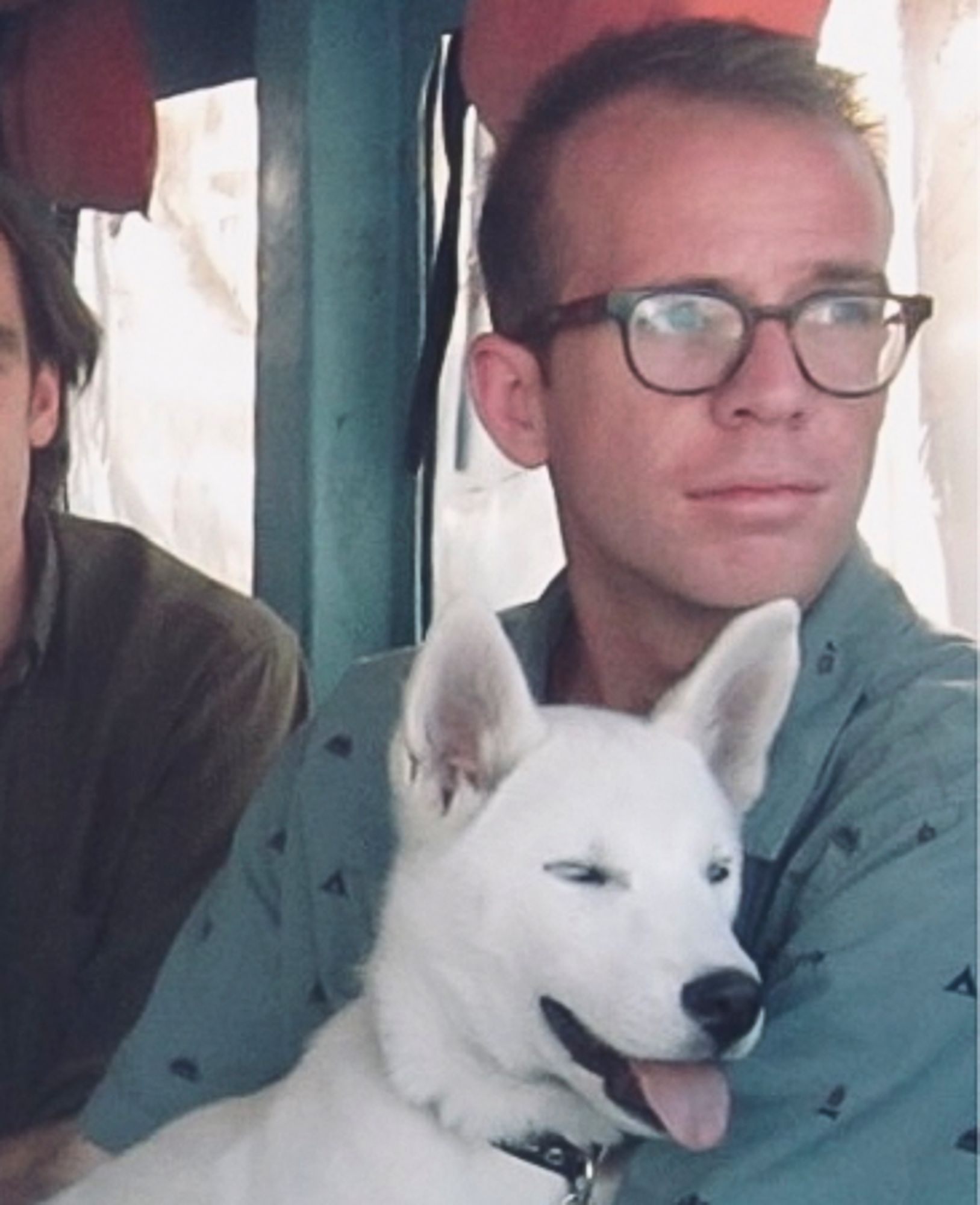 Ben is wearing glasses and has a white dog on his lap