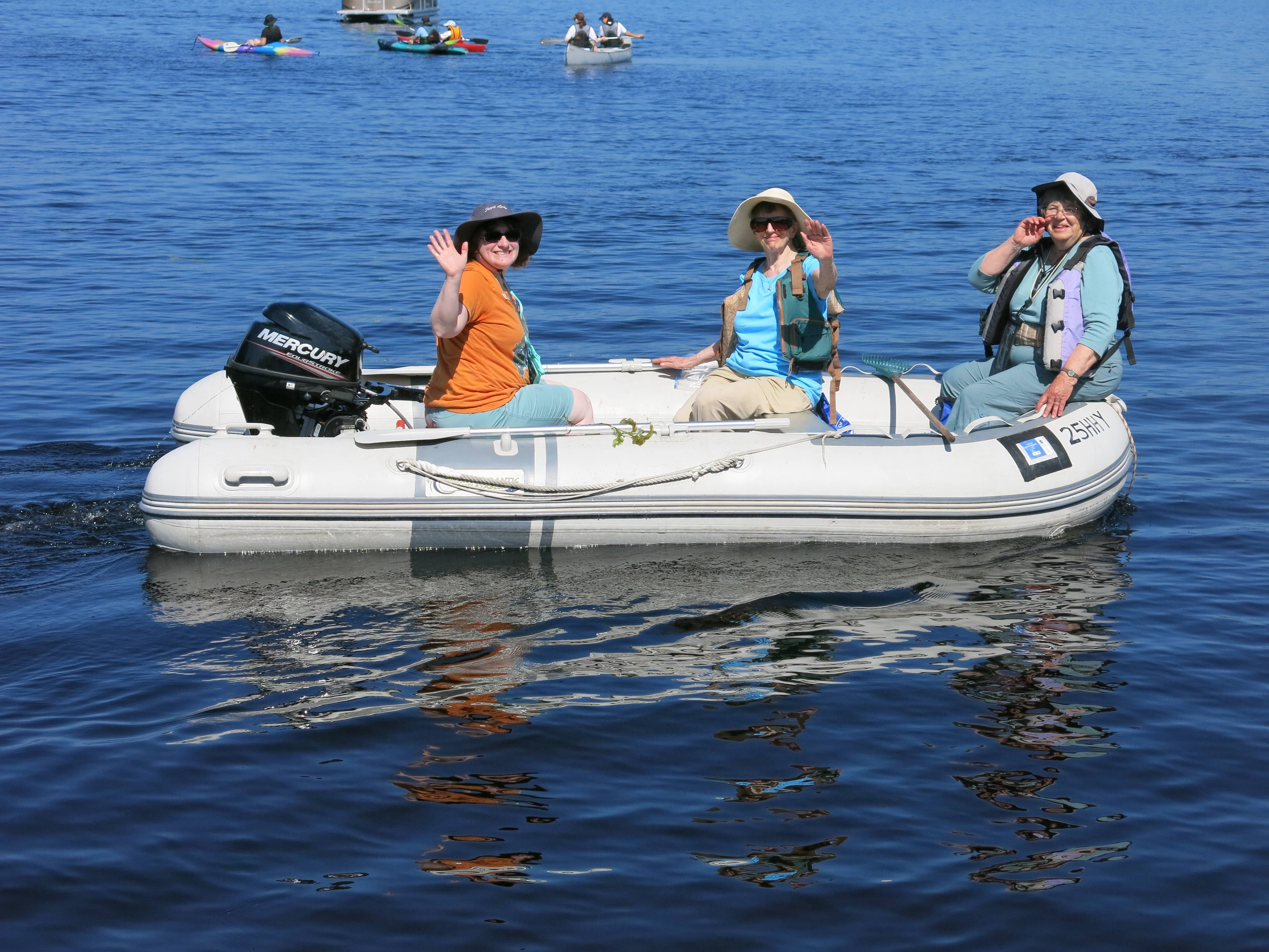 Three volunteers sit in a raft to survey Big Lake