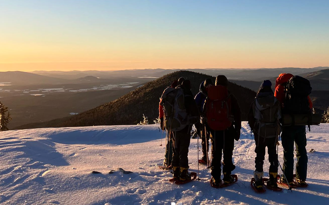 A group of young people hike on a snowy mountain with the Rippleffect team