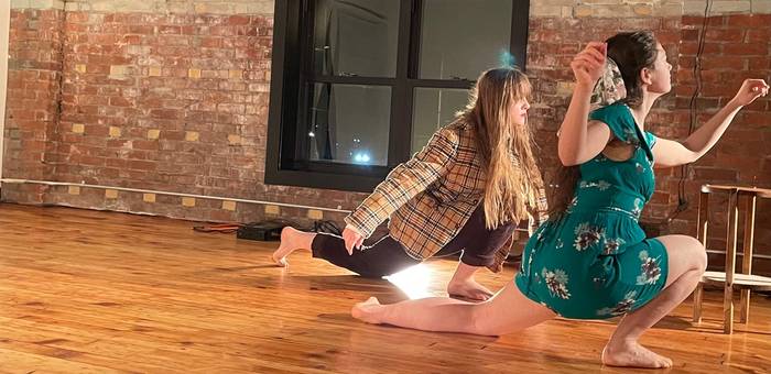 Two dancers perform work on a wooden floor