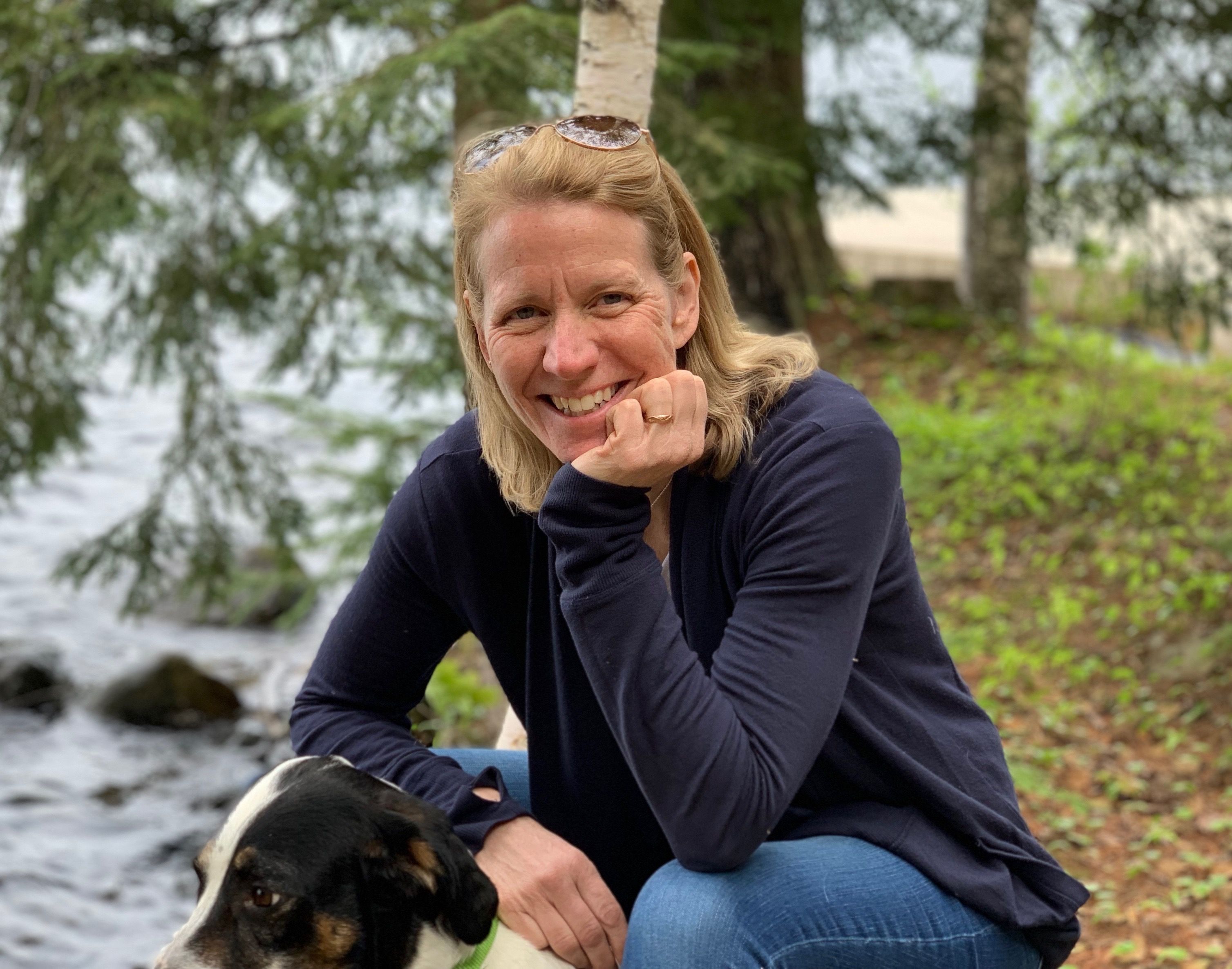 Susan Onion sits outside with her dog, and smiles at the camera