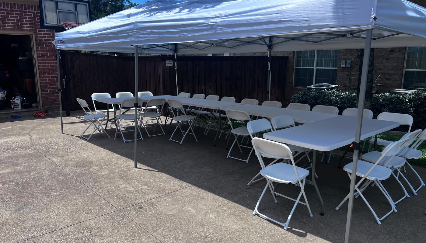 Simply Gathered 6-foot tables lined up end to end with white folding chairs under a 10x20 canopy tent