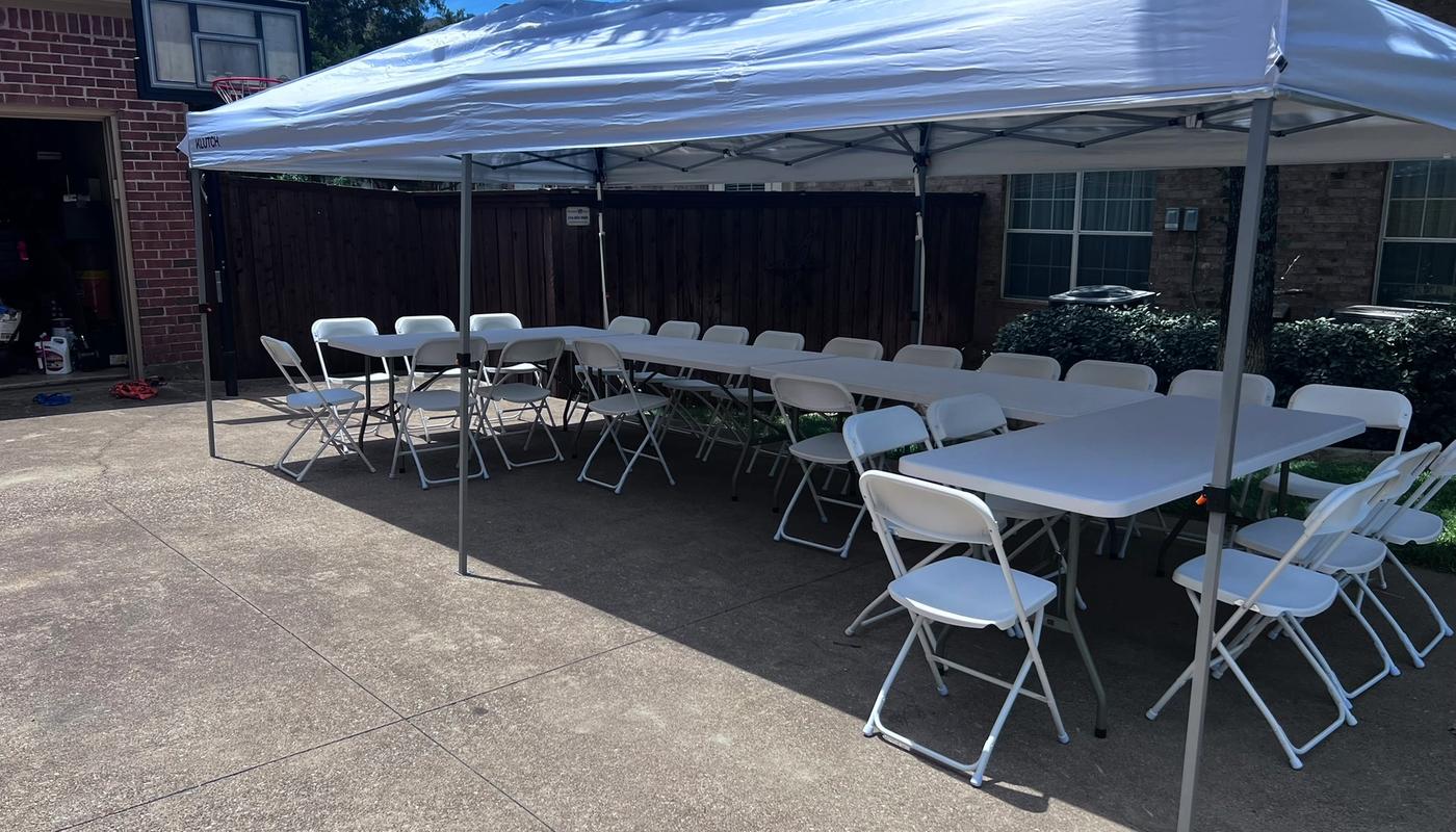 Simply Gathered 6-foot tables lined up end to end with white folding chairs under a 10x20 canopy tent