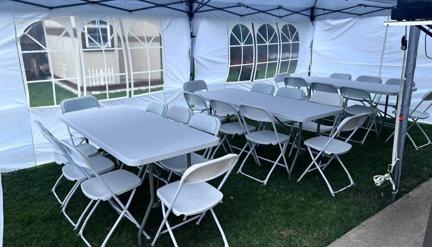 Simply Gathered 10x20 canopy tent with sidewalls over three 6-foot tables and white folding chairs