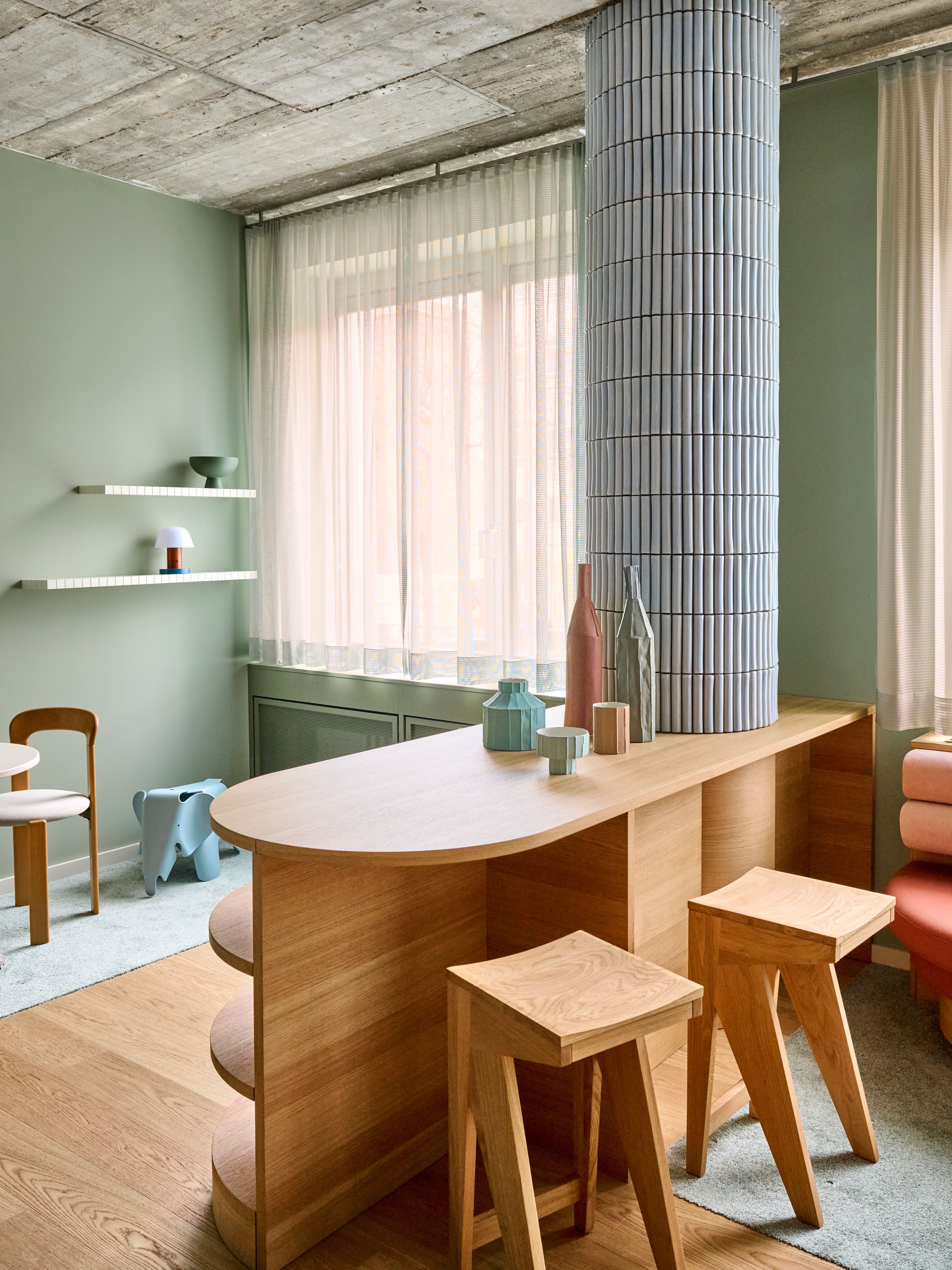 Ein organisch geformter Tresen aus Holz mit farblich abgestimmten Accessoires integriert Funktion und Wohnlichkeit im Designkonzept von Stephanie Thatenhorst.