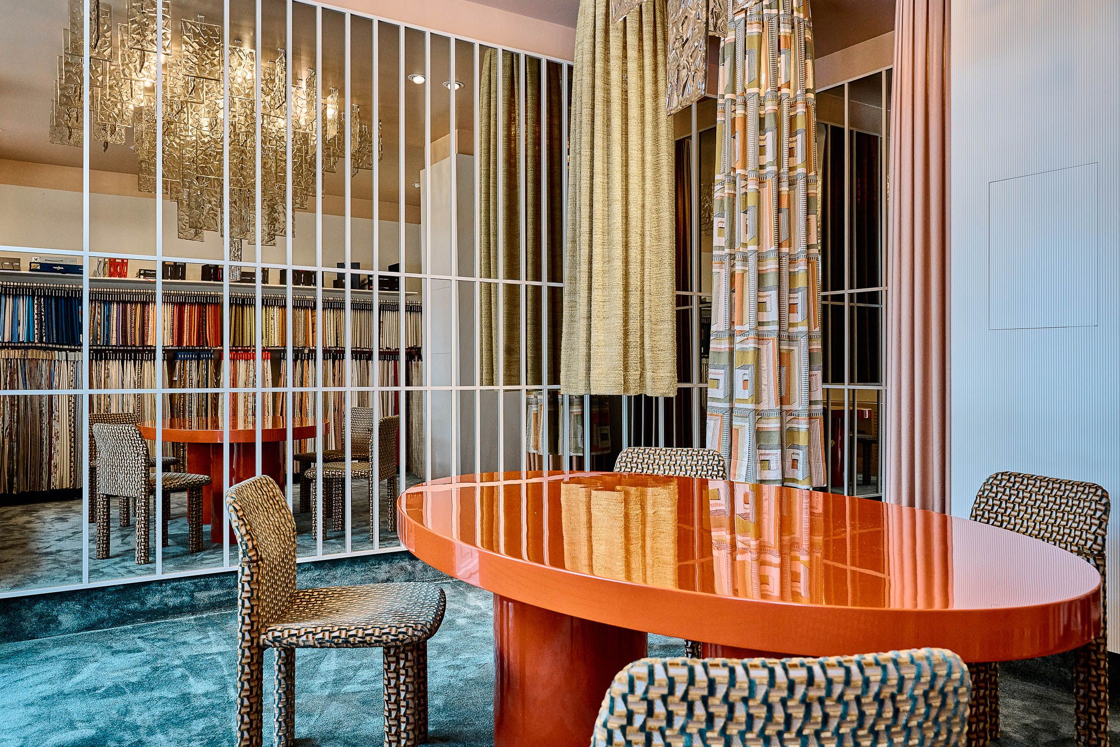 Ein farbstarker Musterraum mit glänzendem Designtisch, strukturierten Stoffen und markanten Formen zeigt die charakteristische Gestaltung der Designerin Stephanie Thatenhorst.