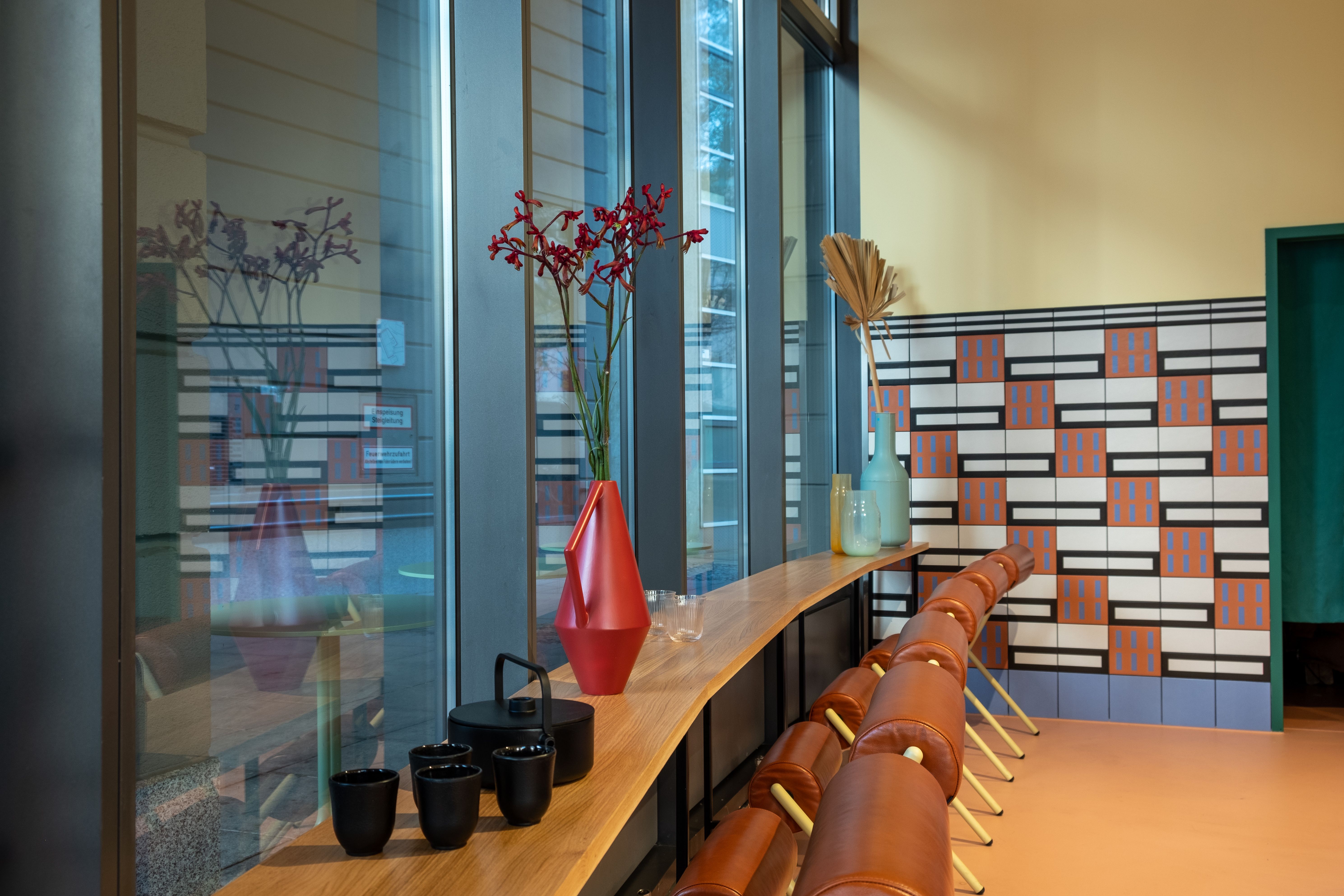 Die Fensterbar mit Lederhockern und skulpturalen Vasen schafft bei By Vu – Asian Restaurant eine urbane Atmosphäre mit hoher Aufenthaltsqualität.