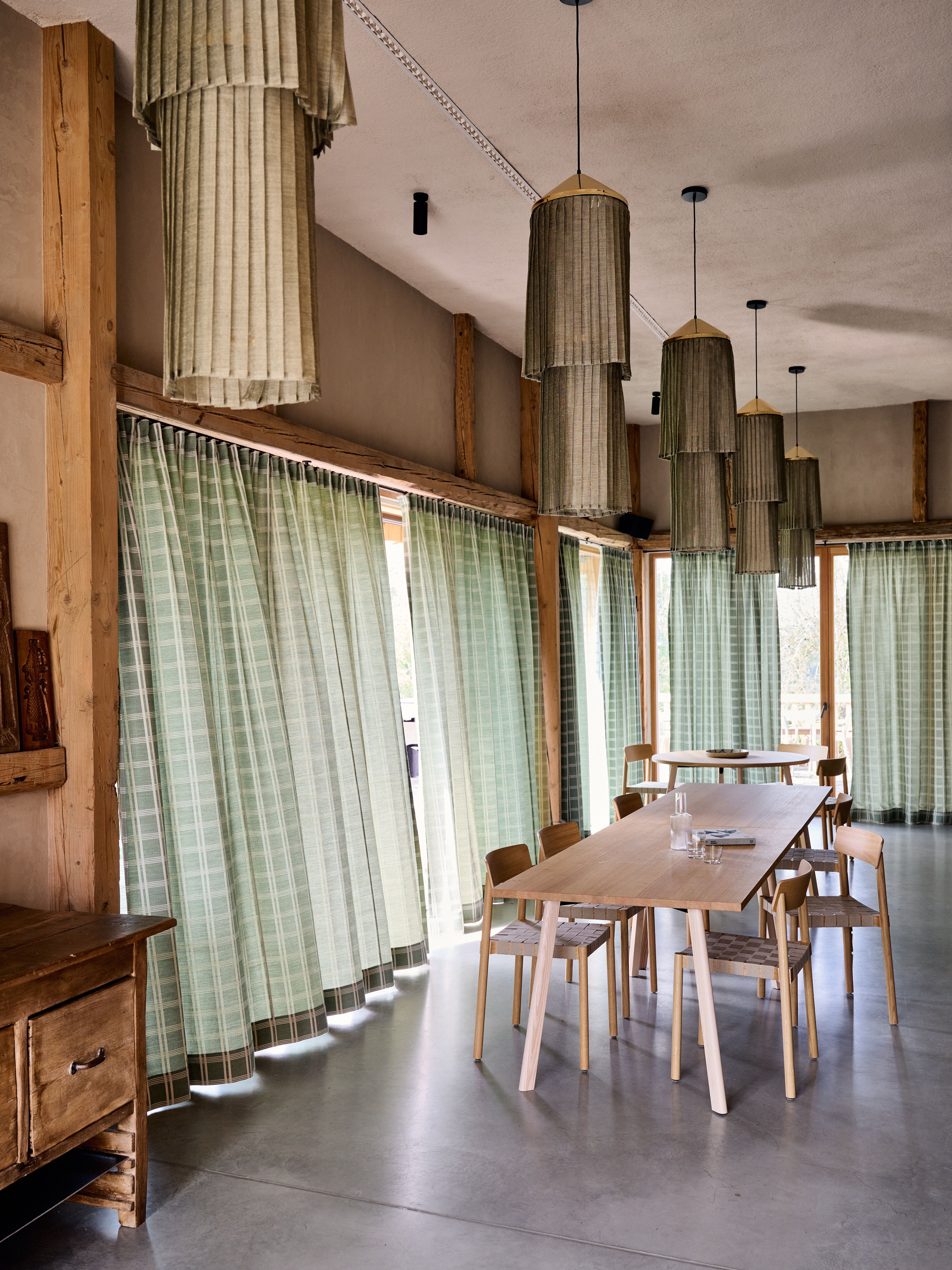 Designed by Stephanie Thatenhorst, vereint dieser textilpoetisch inszenierte Speisebereich handwerkliches Holzmobiliar, weich gefiltertes Tageslicht und stoffliche Vertikalität zu einer ruhigen, ausgewogenen Raumharmonie.