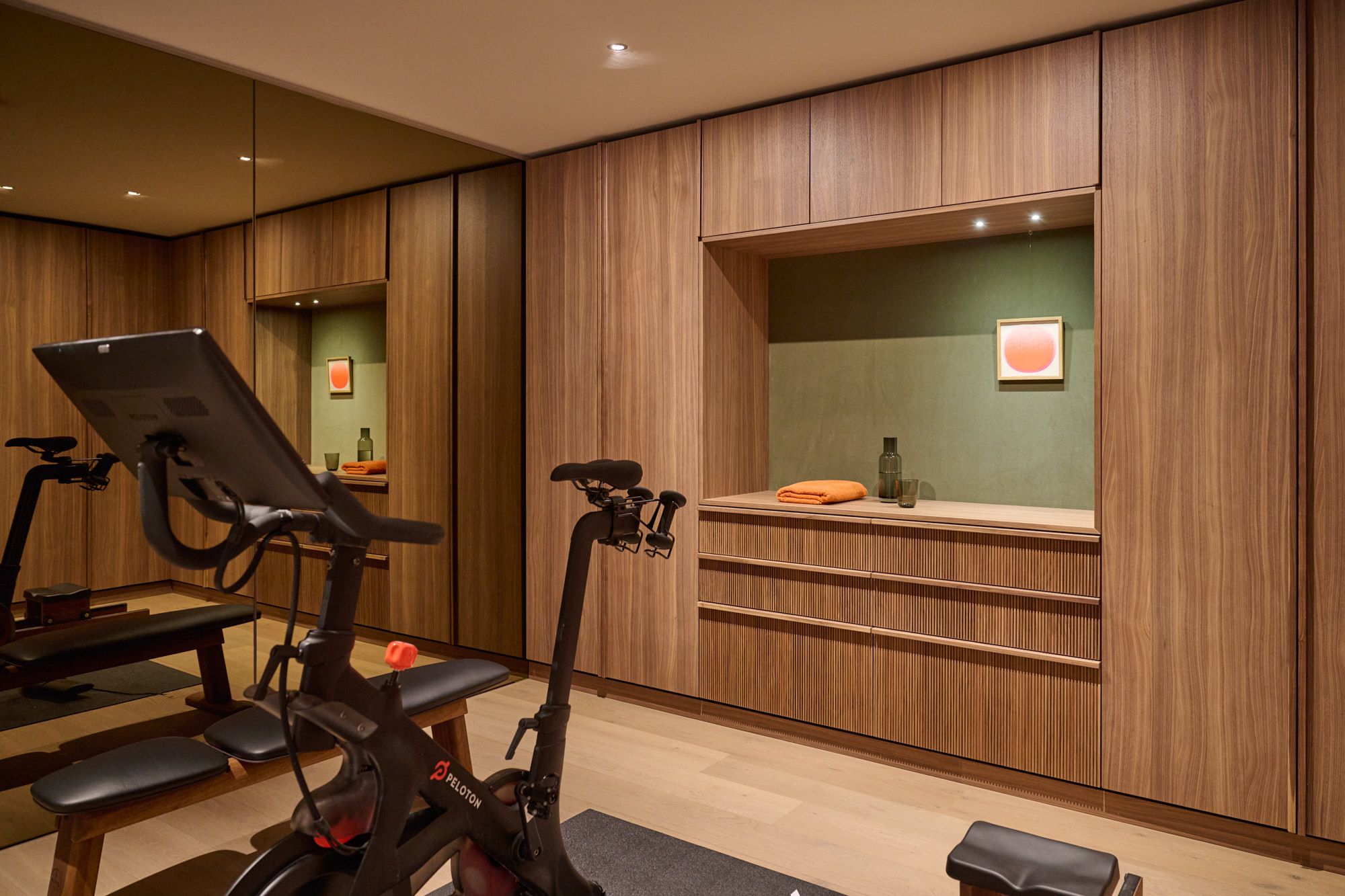 Hochwertiger Home-Gym-Bereich mit warmen Holzfronten, integrierten Nischen und modernem Equipment für ein stilvoll motivierendes Trainingsambiente.