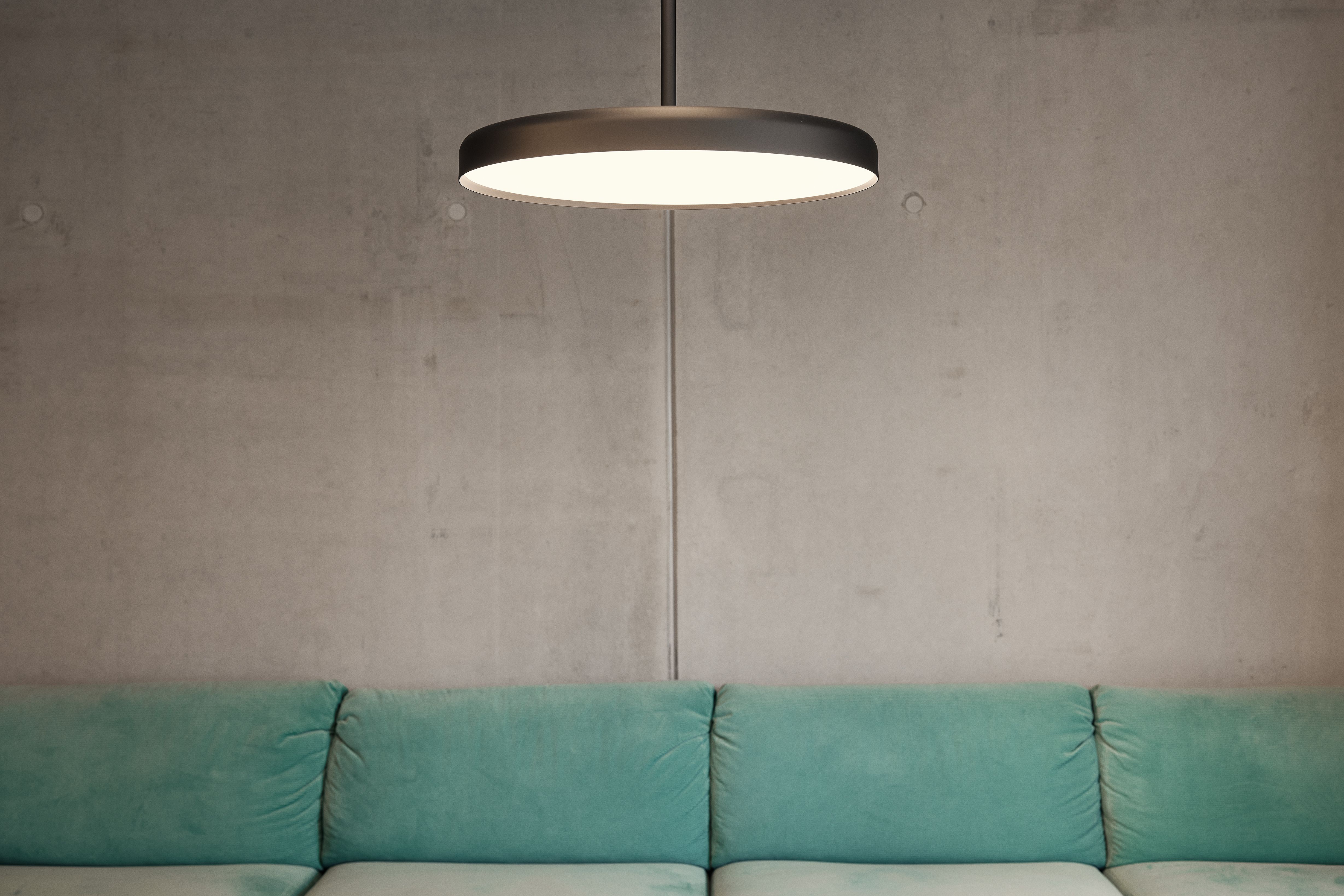 Die minimalistische Pendelleuchte über dem Sitzbereich ergänzt das klare Gestaltungskonzept der Zahnarztpraxis Stephanie Thatenhorst in Kempten.