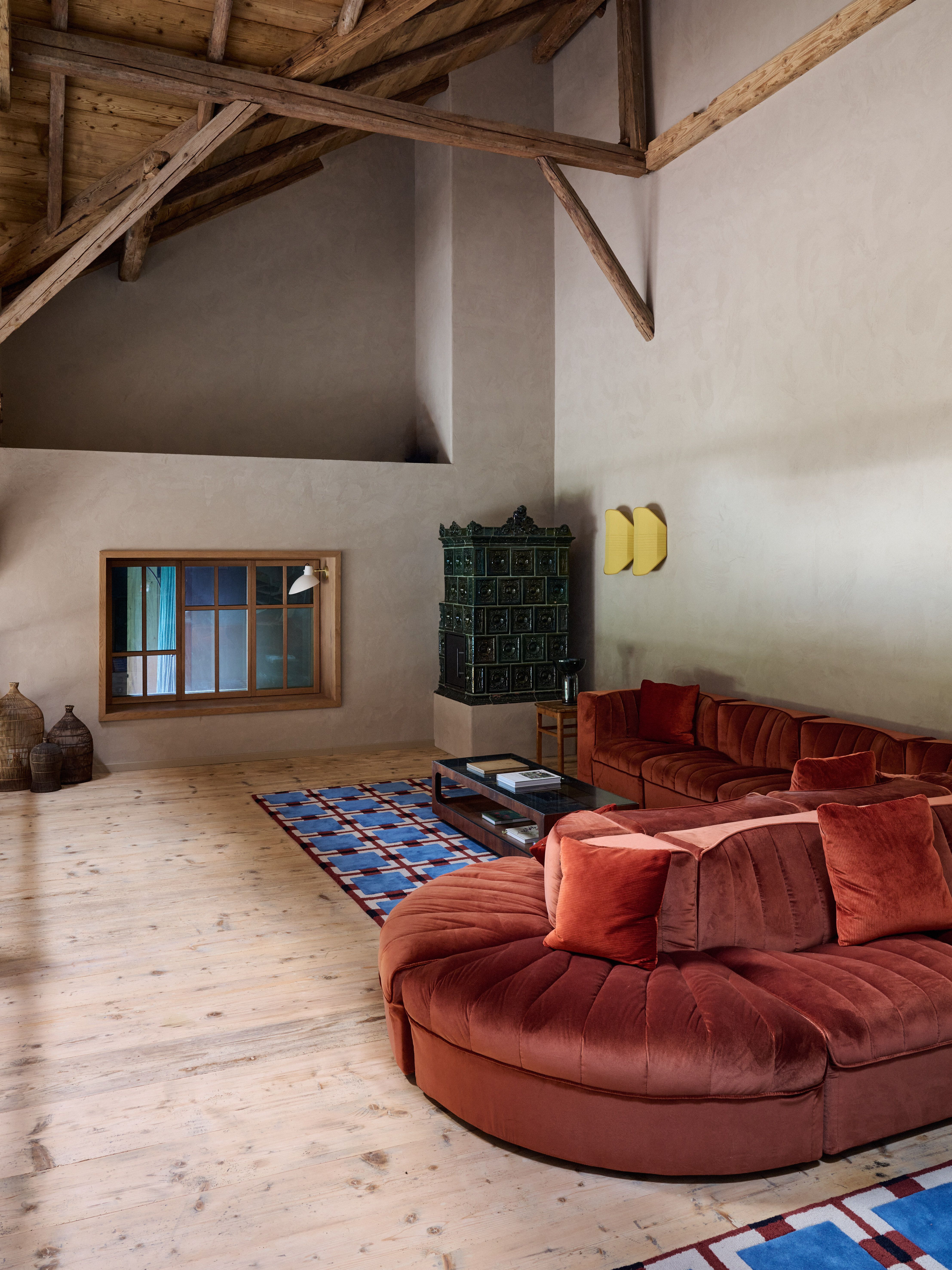 Samtsofa und historischer Kachelofen im hohen Wohnraum, designed by Stephanie Thatenhorst