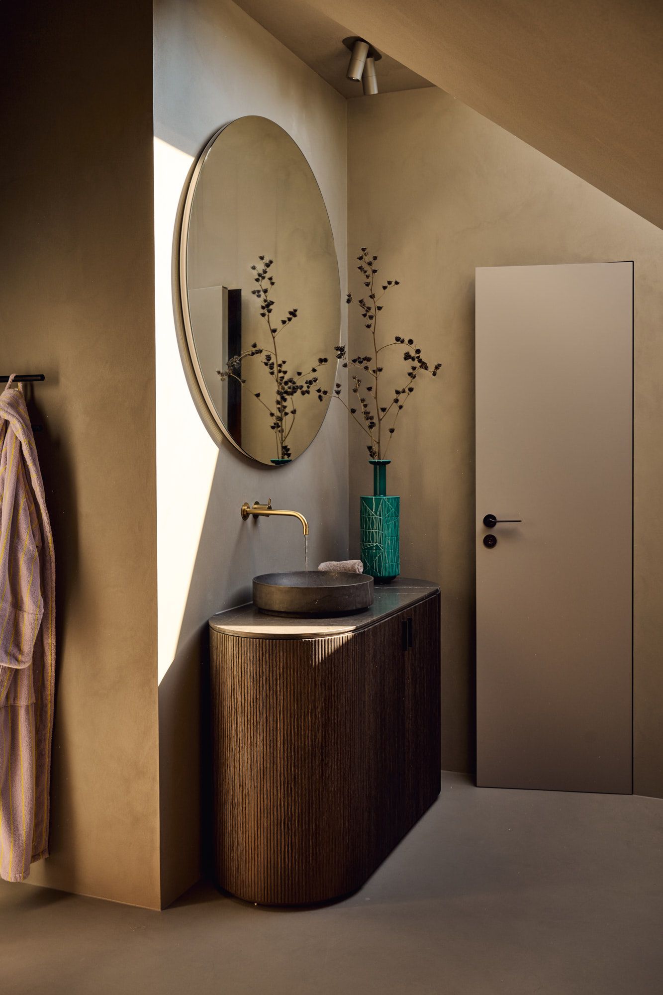 Eleganter Waschtisch mit runder Spiegelkulisse, warmen Naturtönen und goldener Armatur für ein harmonisches, modernes Badezimmer