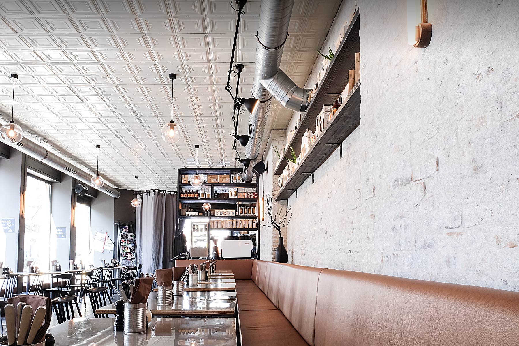 Die lange Sitzbank entlang der Holzwand prägt den Raum des Occam Deli und schafft eine klare Struktur für den Gästebereich.