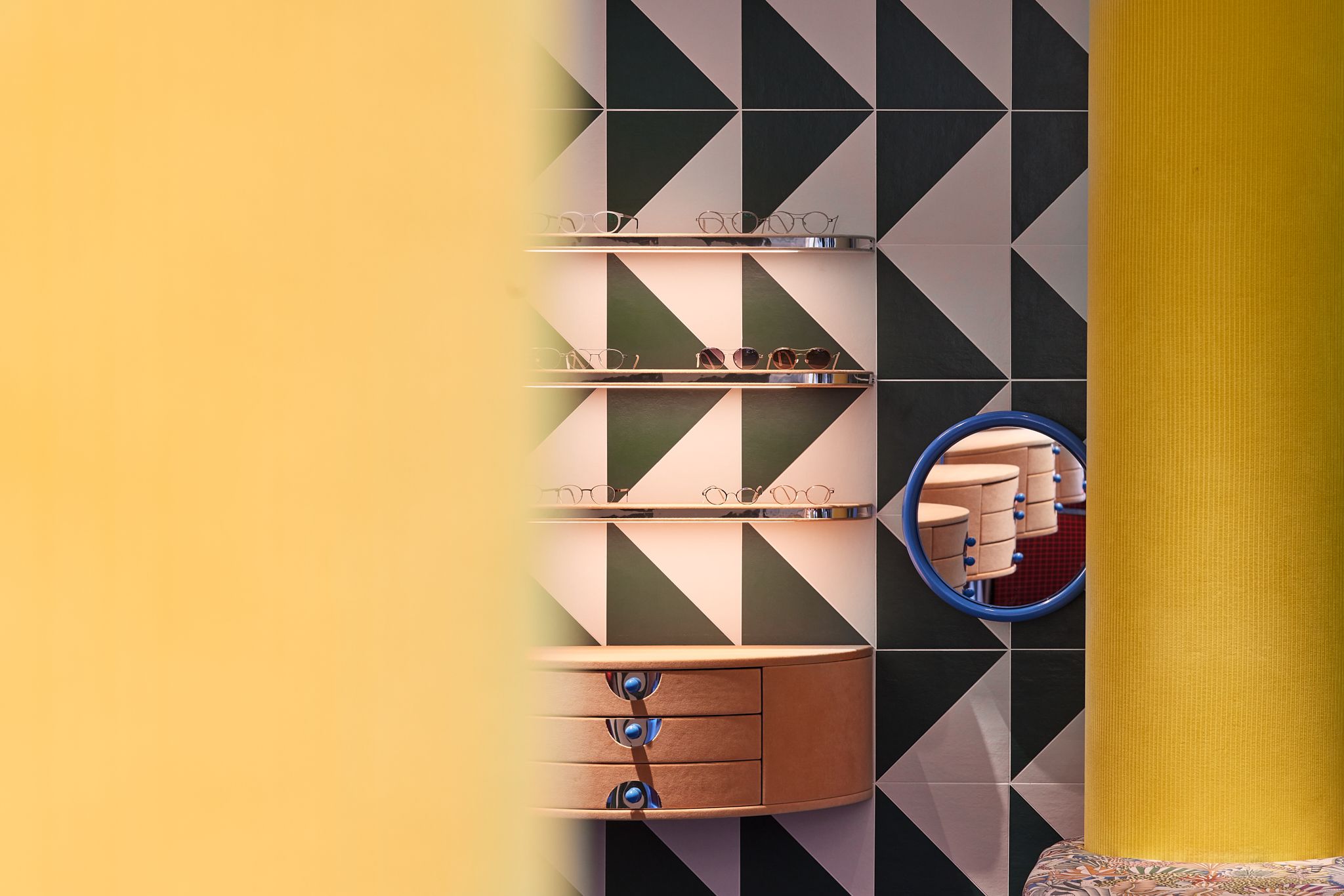 Dieses Motiv zeigt die markante gelbe Säule mit gepolsterter Sitzbank im Rookies – Eyewear for Kids, die Stephanie Thatenhorst als farbintensiven Mittelpunkt des Raumes inszeniert.