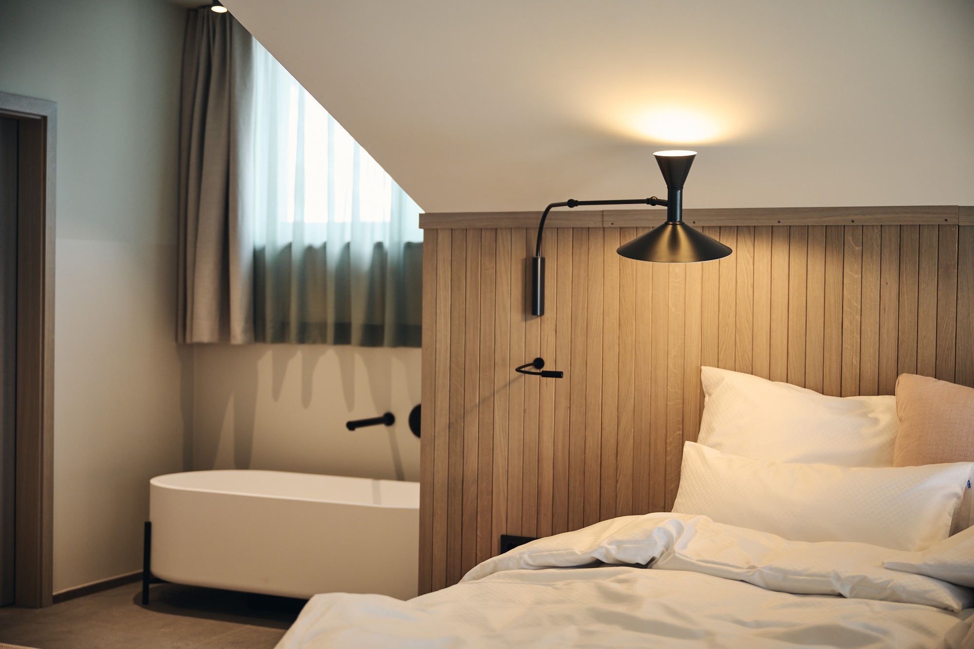 Das Schlafzimmer unterm Dach des Ullrhaus Hotels zeigt Stephanie Thatenhorsts Talent, warme Materialien mit architektonischer Klarheit zu kombinieren.