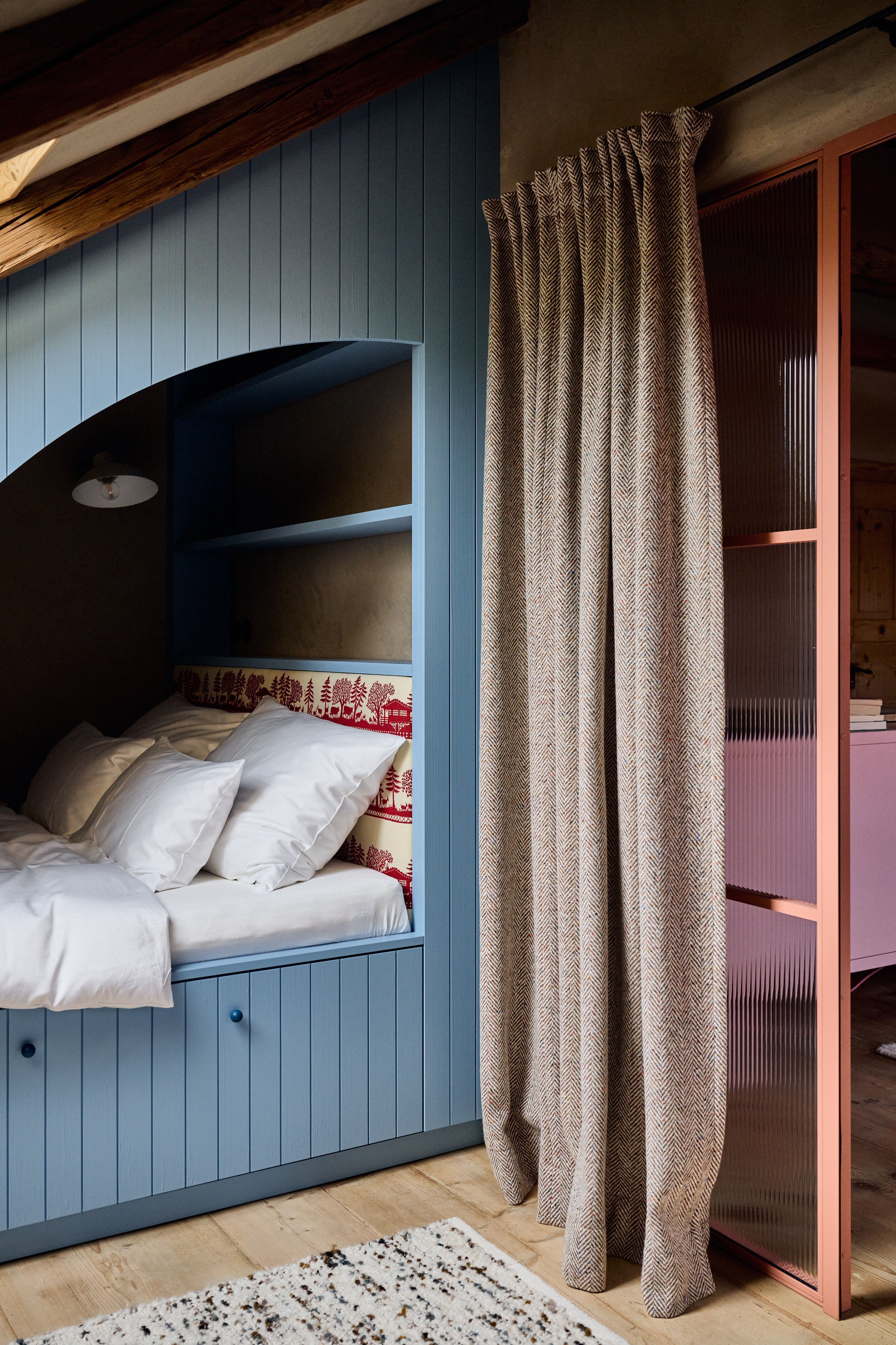 Einbau-Schlafkoje in staubigem Blau mit gesticktem Alpenmotiv-Rückpaneel und schweren Wollvorhängen als moderner Chalet-Rückzugsort