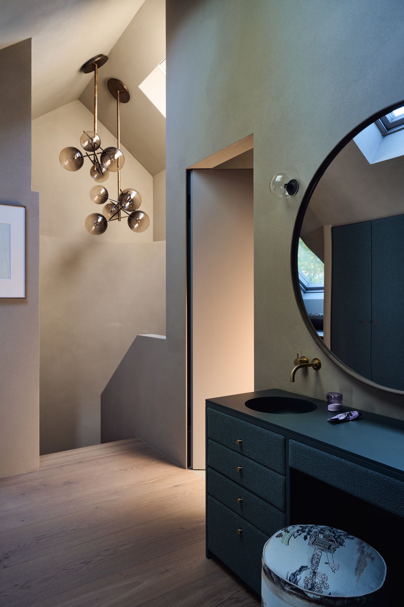 Elegantes Interieur von Stephanie Thatenhorst mit skulpturalem Lichtobjekt, runder Spiegelarchitektur und texturierten Badmöbeln.