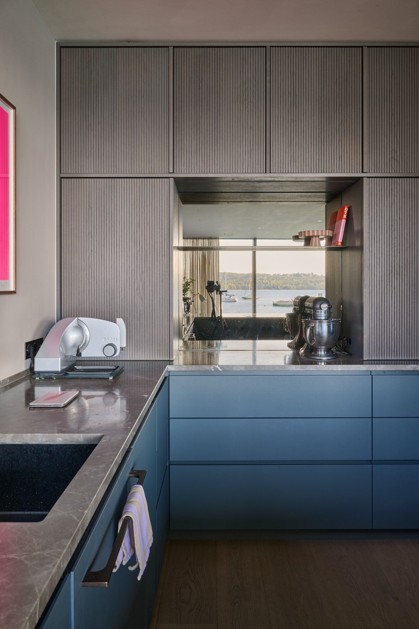 Moderne Küche mit strukturierten Fronten, tiefblauen Unterschränken und eleganter Steinplatte für ein zeitlos harmonisches Gesamtbild.