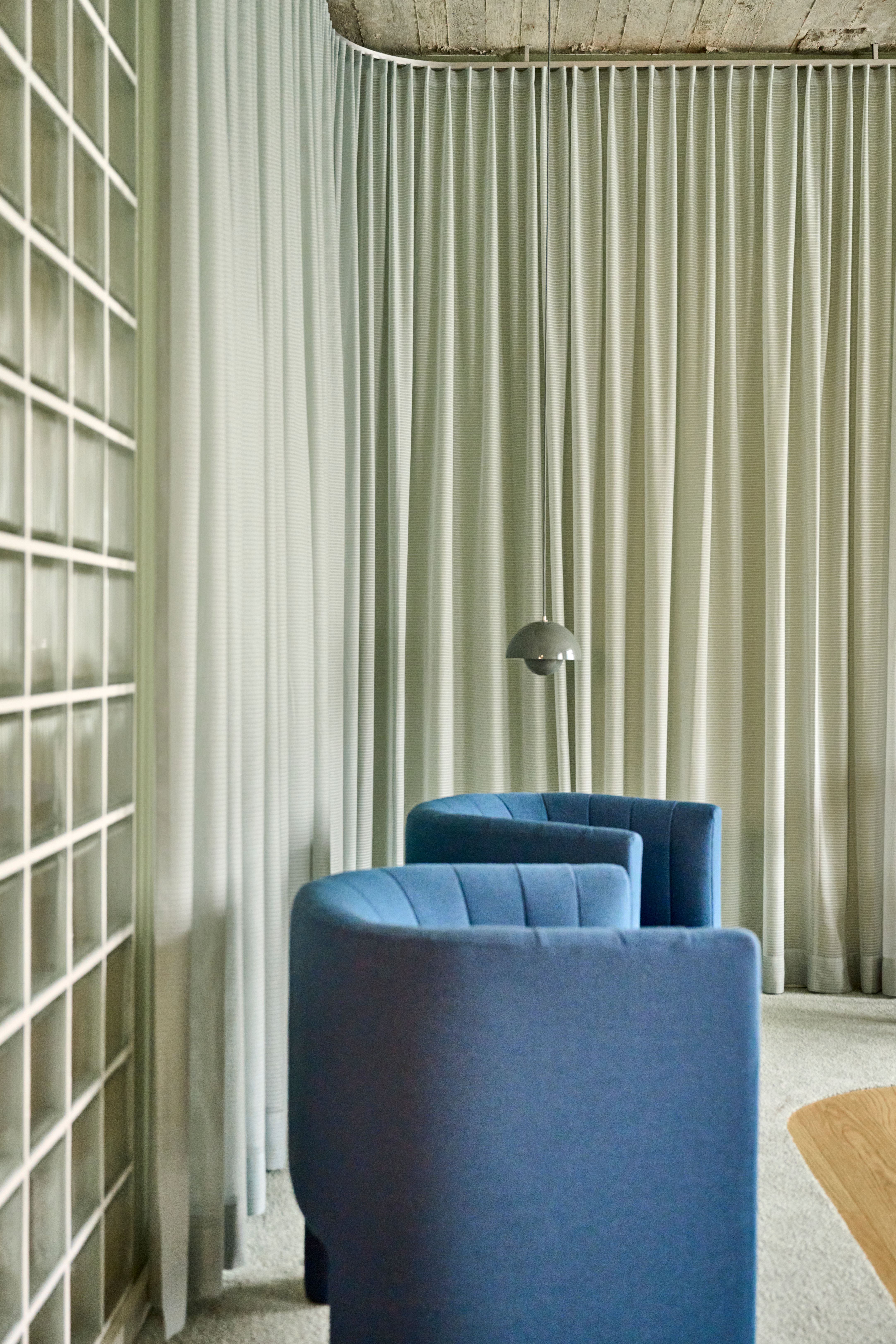 Wartebereich mit blauen Sesseln und Vorhangarchitektur, Design von Stephanie Thatenhorst für Lieblingszahnarzt.
