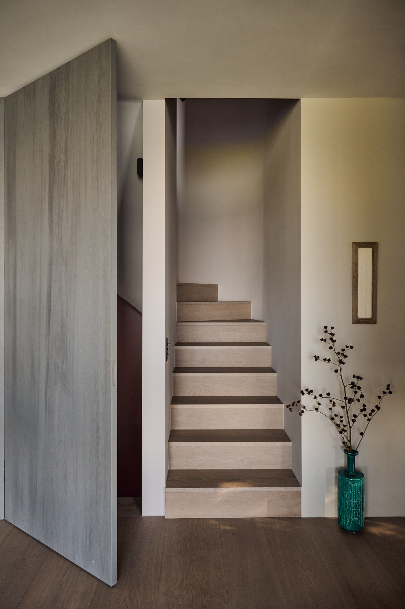 Puristische Holztreppe mit sanfter Lichtführung und natürlichen Materialien für ein harmonisch modernes Wohnambiente.