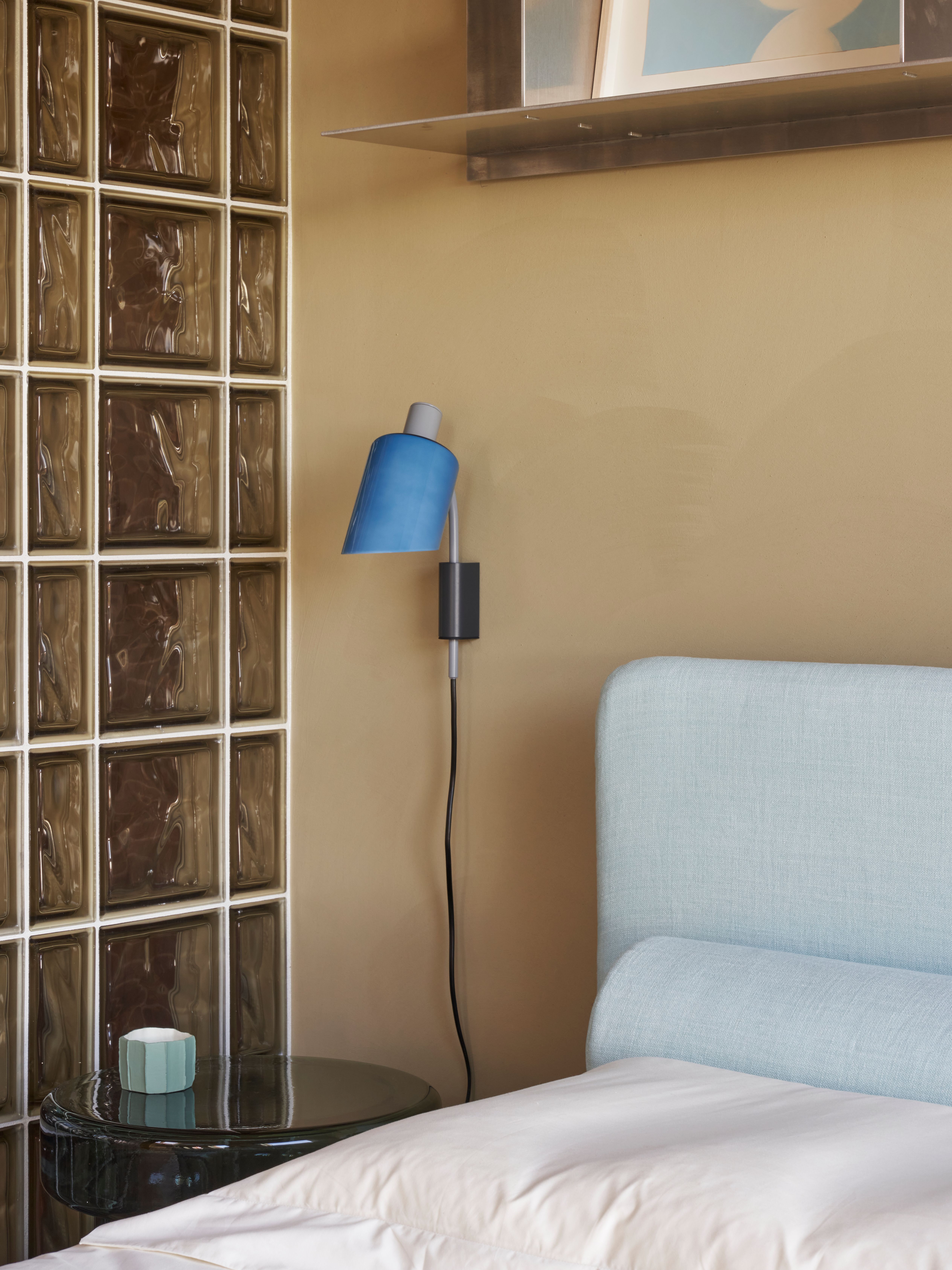 Die harmonische Kombination aus Glasbausteinen, hellblauem Bettkopfteil und skulpturaler blauer Wandleuchte wurde von Stephanie Thatenhorst AD New Perspectives designt.