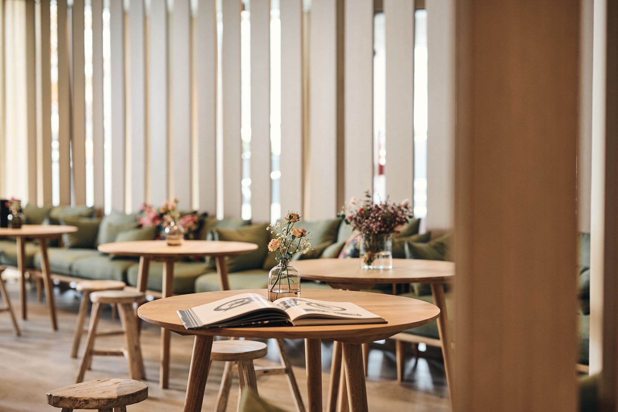 Die filigranen Blumenarrangements auf den Holztischen unterstreichen Stephanie Thatenhorsts feines Gespür für natürliche Details im Ullrhaus.