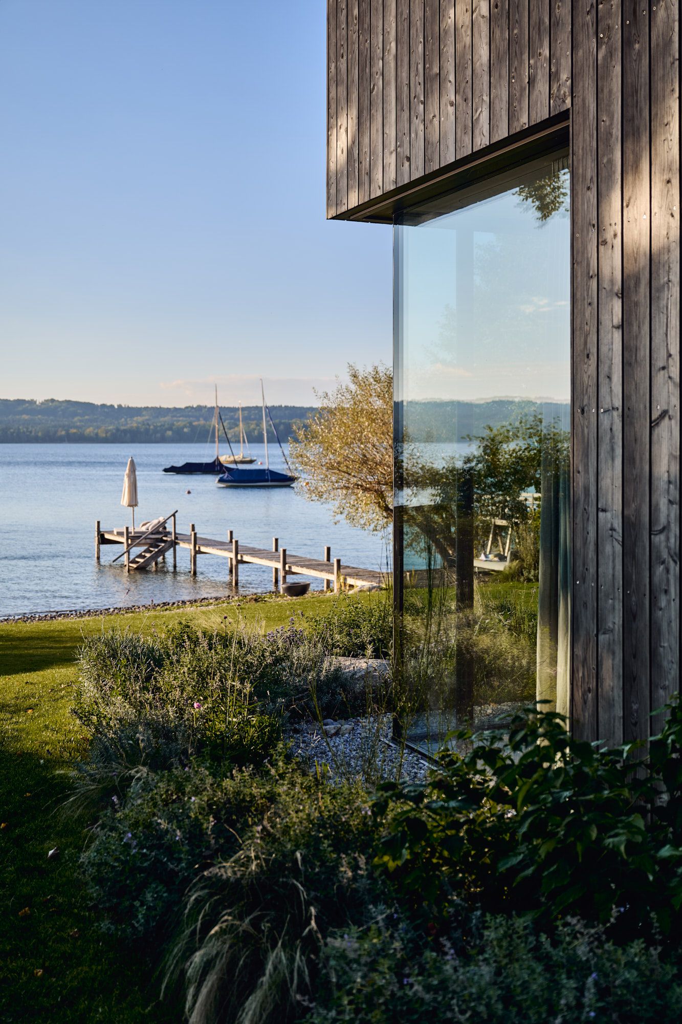 Ein harmonisch inszeniertes Seehaus, in dem natürliche Materialien, klare Architektur und die unmittelbare Nähe zum Wasser zu einem modernen Rückzugsort verschmelzen.