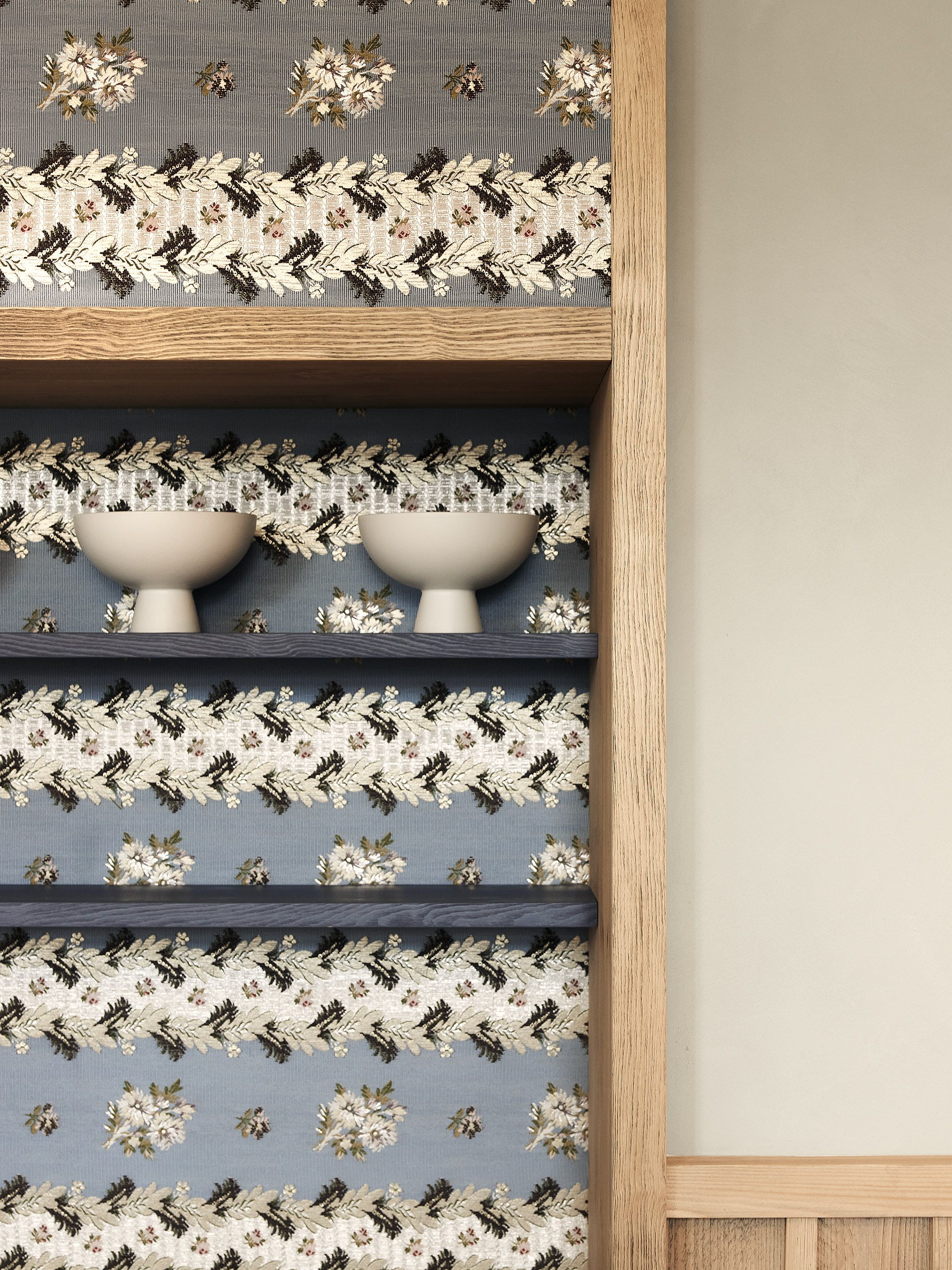 Die dekorative Stofftapete mit floralen Motiven bildet ein gestalterisches Highlight und betont die handwerkliche Atmosphäre des Hauses.