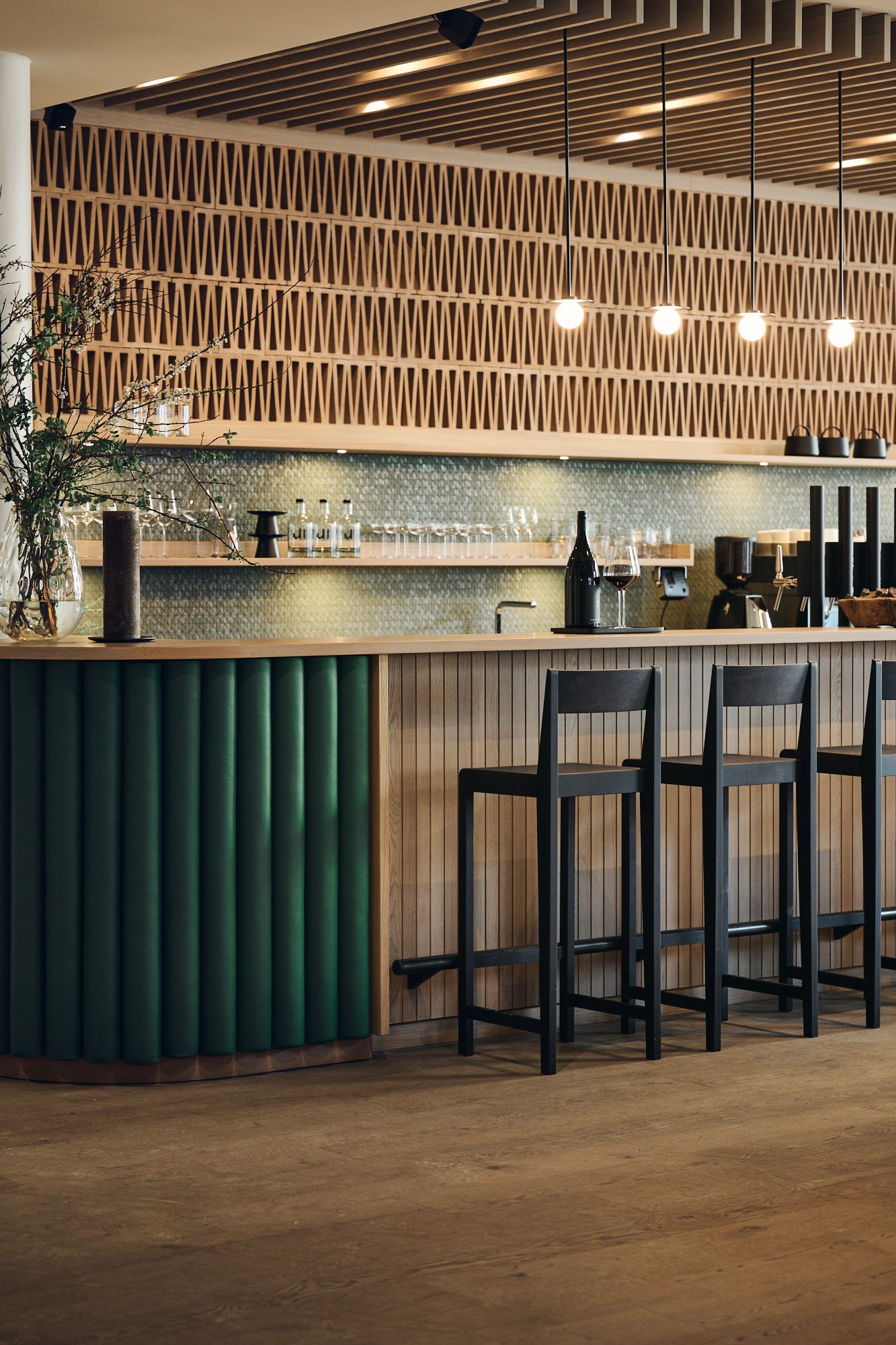 Die stilvoll gestaltete Bar im Ullrhaus Hotel zeigt die charakteristische Designsprache von Stephanie Thatenhorst mit warmen Holzstrukturen und tiefgrünen Akzenten.