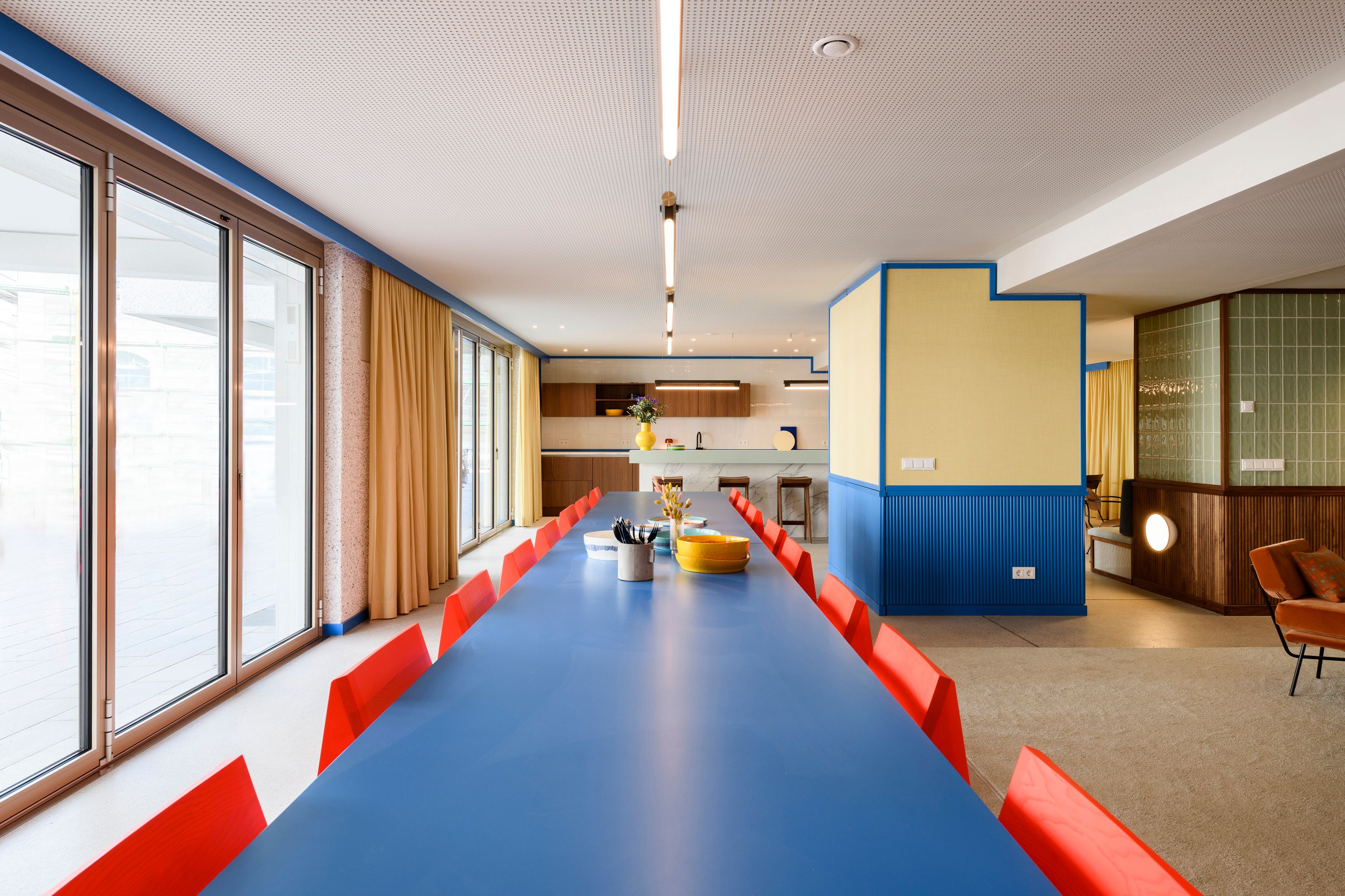 Der lange blaue Gemeinschaftstisch mit roten Stühlen, designt von Stephanie Thatenhorst, prägt die kommunikative Atmosphäre der Kupa – Kitchen & Working Lounge.