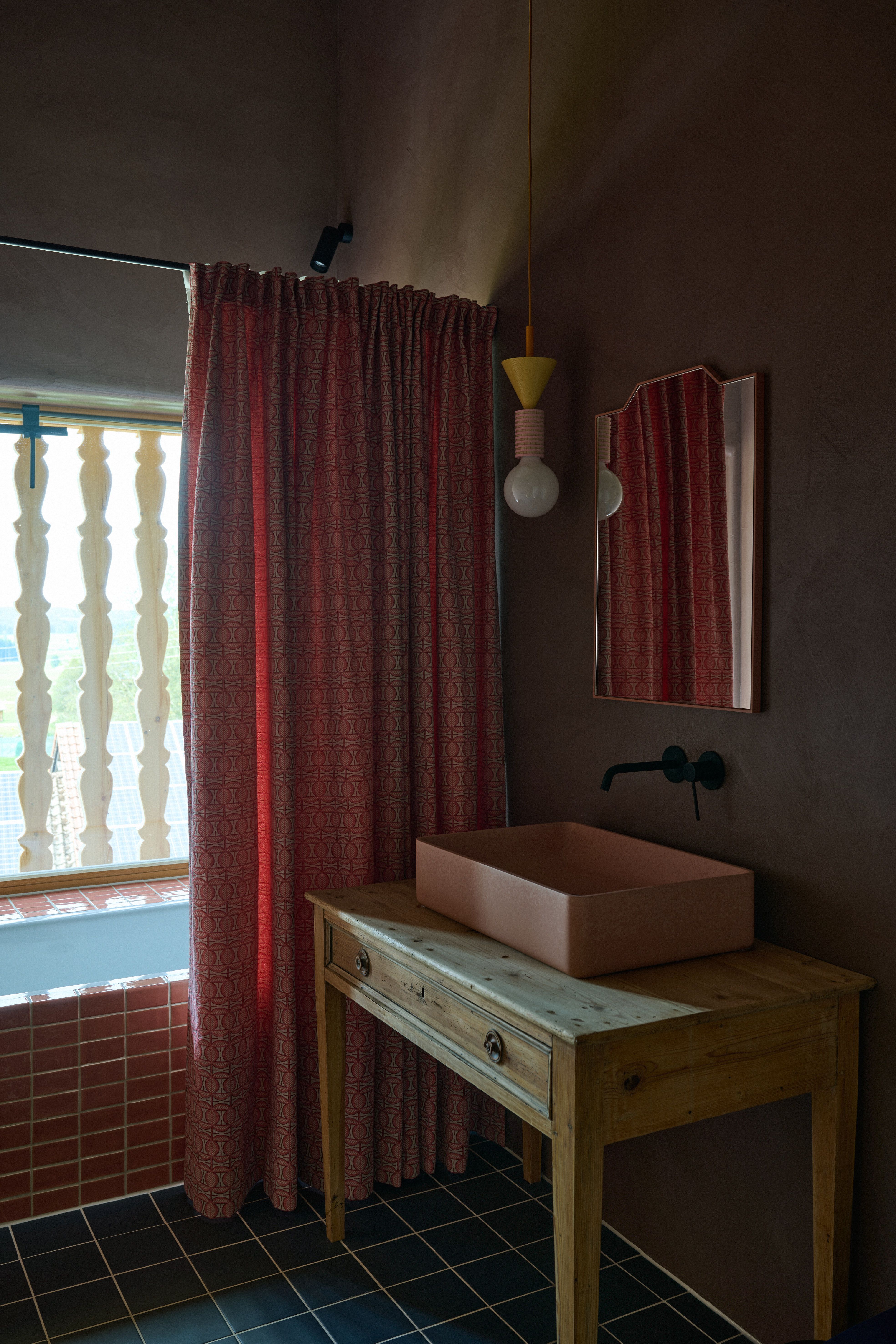 Zeitgenössisches Bad mit pastellfarbenem Aufsatzbecken, Vintage-Holzkonsole und textiler Privatsphäre, gestaltet von Stephanie Thatenhorst.