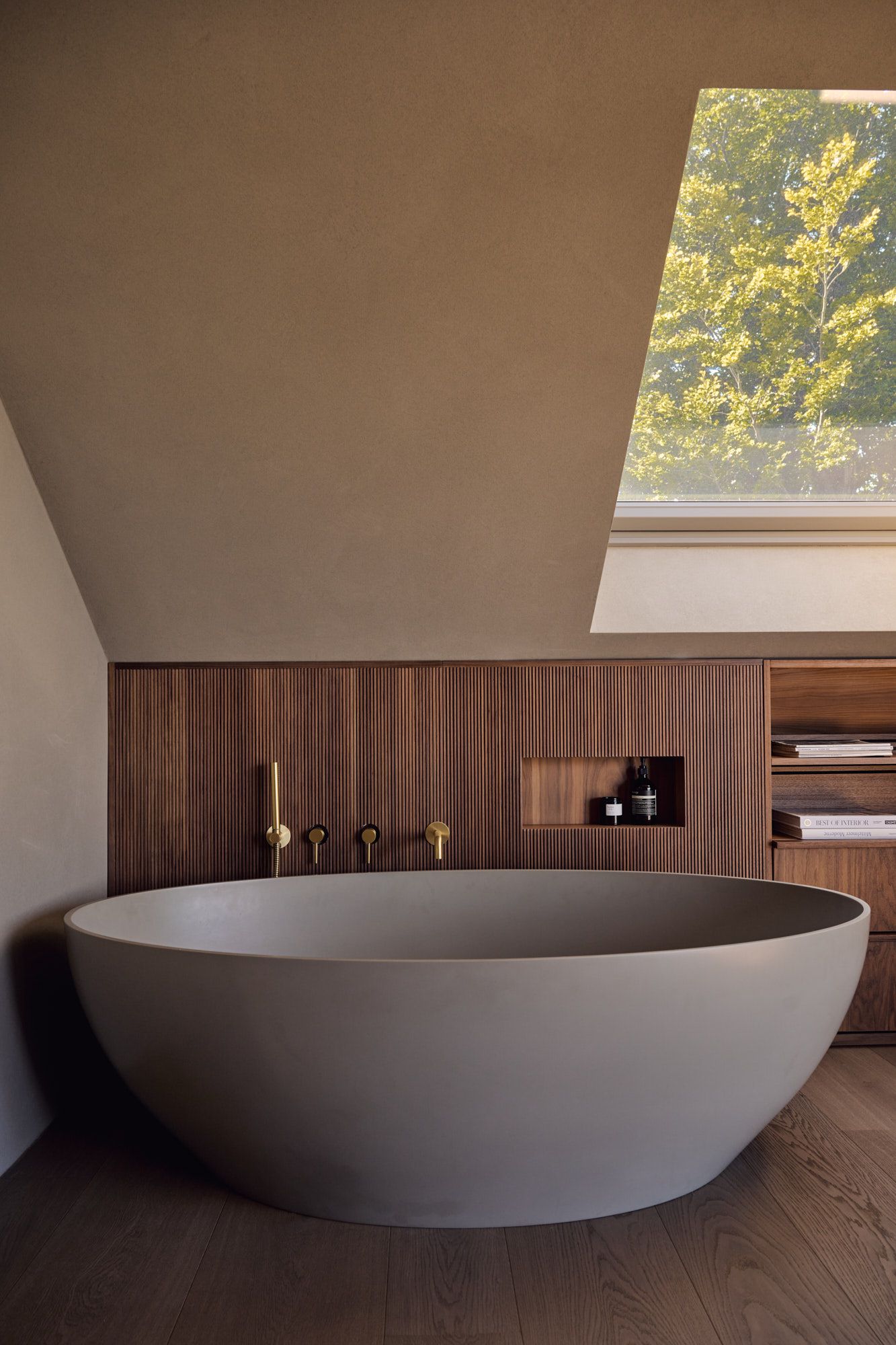 Freistehende Designer-Badewanne vor gerillter Holzverkleidung für ein warmes, modernes Spa-Ambiente