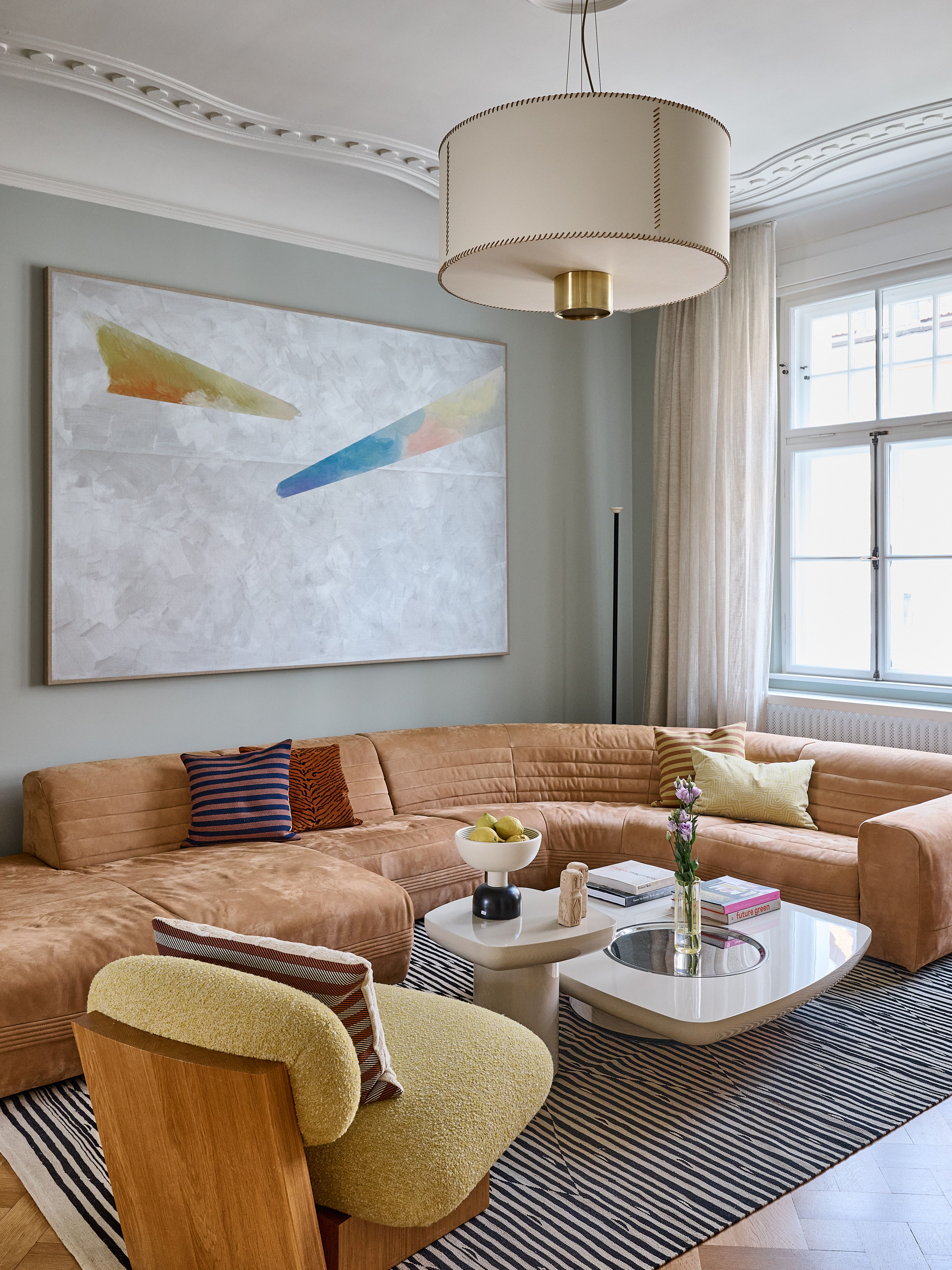 Ein stilvoll kuratiertes Wohnzimmer der Showflat im Stephanie-Thatenhorst-Design mit harmonischen Farbtönen, ikonischen Designerstücken und moderner Kunst schafft eine elegante, zeitgemäße Interior-Atmosphäre – ideal für hochwertiges, exklusives Wohnen.