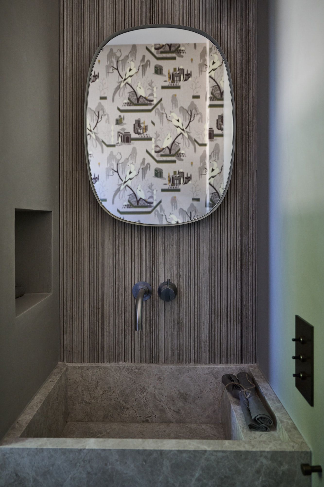 Charakterstarkes Gäste-WC von Stephanie Thatenhorst mit strukturierten Wandpaneelen, Steinwaschbecken und ausdrucksstarker Spiegel-Inszenierung.