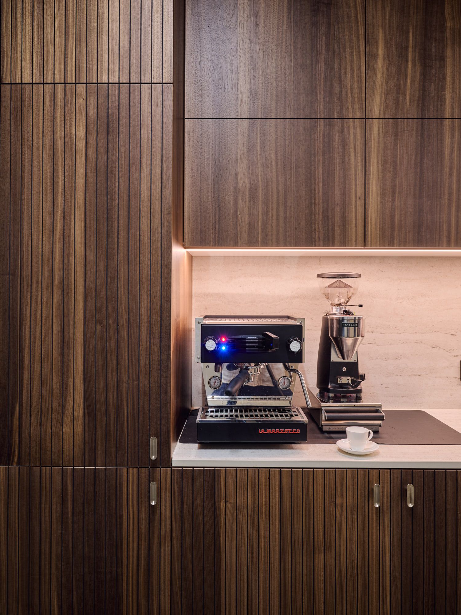 Im Büro Hass Dross Theiss entsteht durch hochwertiges Nussbaumholz, präzise Lichtführung und professionelle Barista-Technik eine elegant gestaltete Kaffeestation von Stephanie Thatenhorst.
