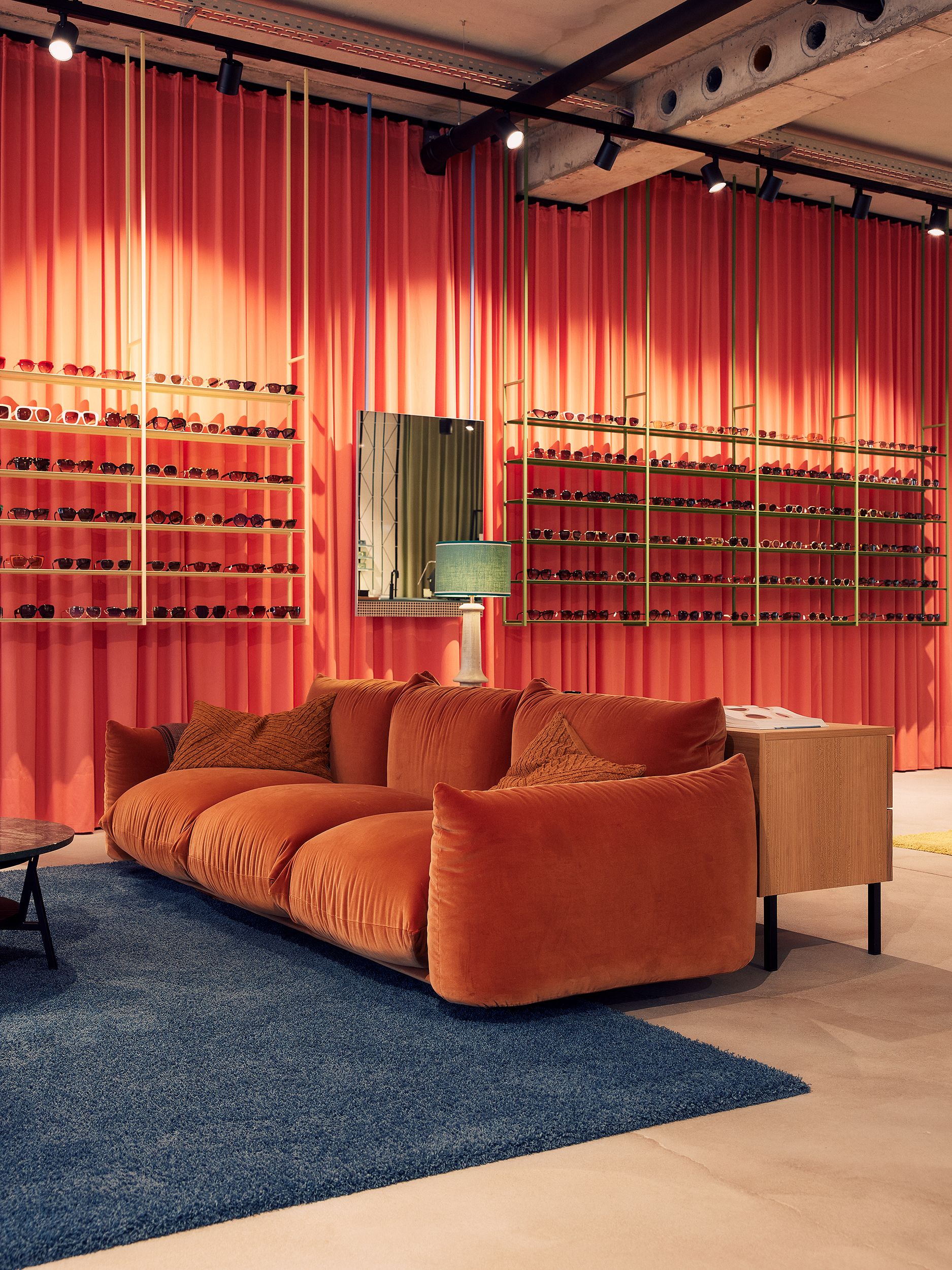 Die loungige Brillenwand mit samtbezogenem Sofa wurde von Stephanie Thatenhorst für Christian Bartels Optik gestaltet.