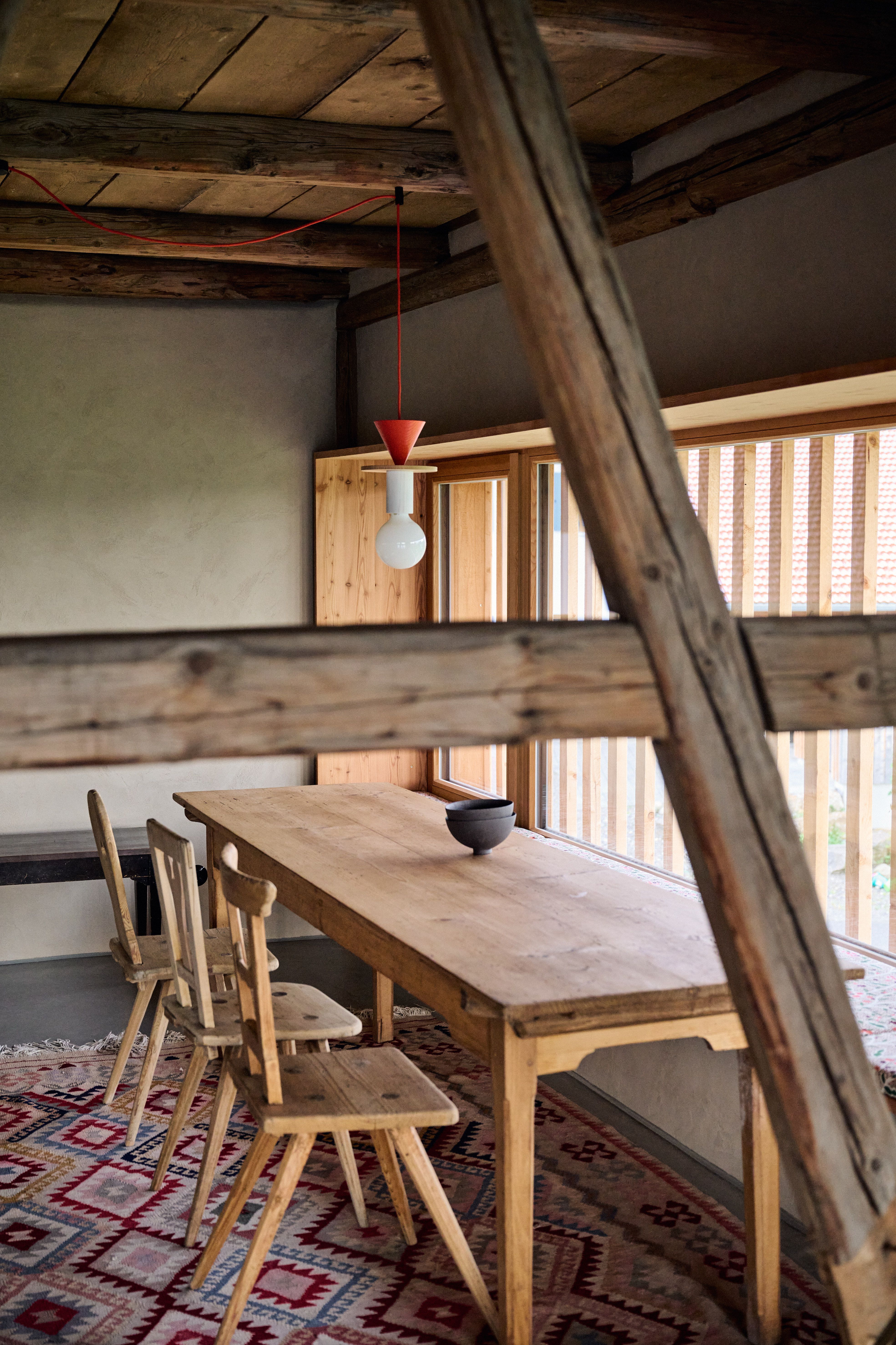 Im Essbereich trifft ein puristischer Massivholztisch auf eine spielerische Leuchteninstallation, wodurch Stephanie Thatenhorst subtil historische Bausubstanz mit farbintensivem Designakzent verwebt.