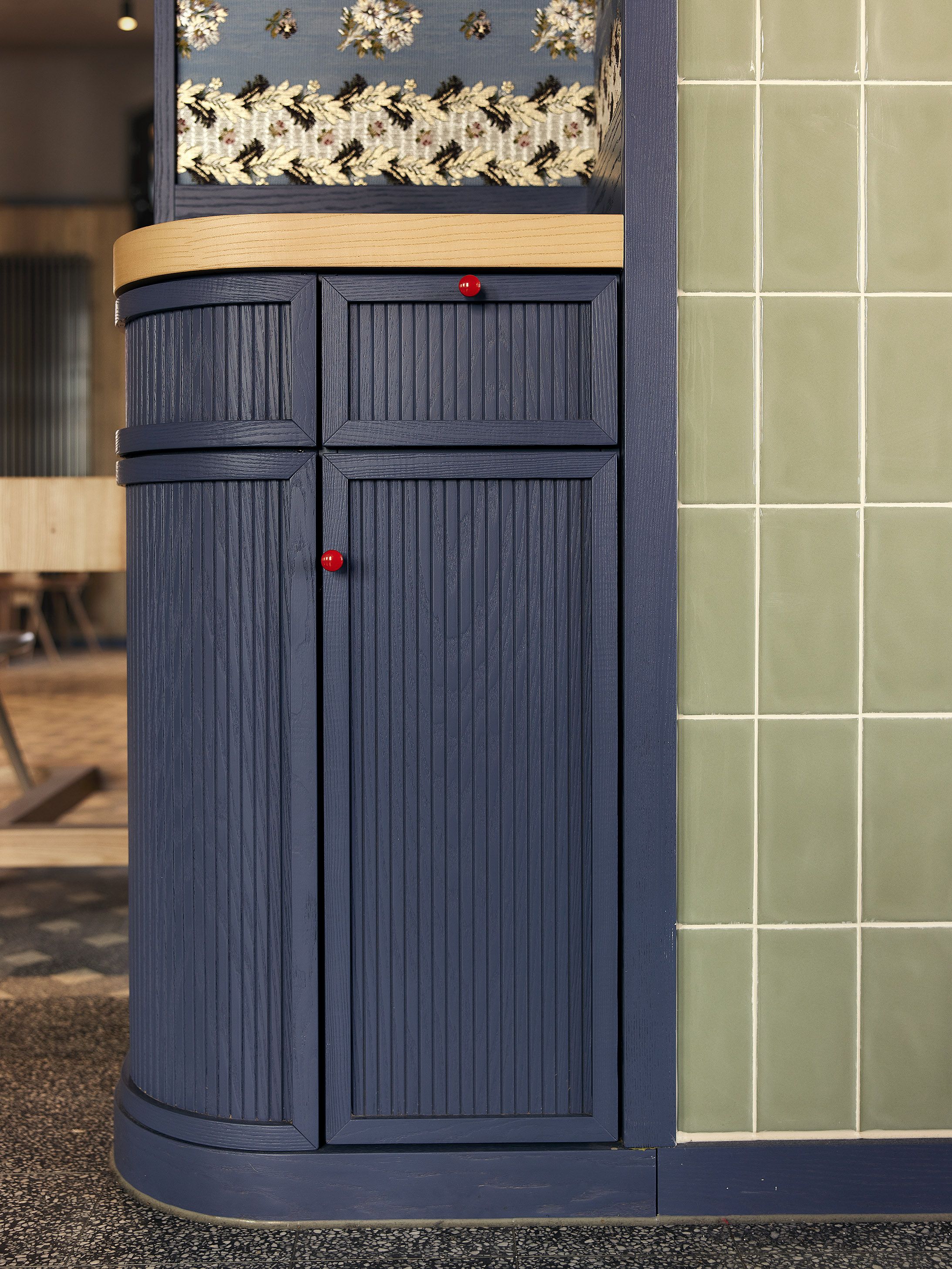 Die elegant gearbeitete Thekenecke setzt mit tiefblauem Holz und feinen Strukturdetails ein charakteristisches Designstatement von Stephanie Thatenhorst im Benediktiner Weissbräuhaus.