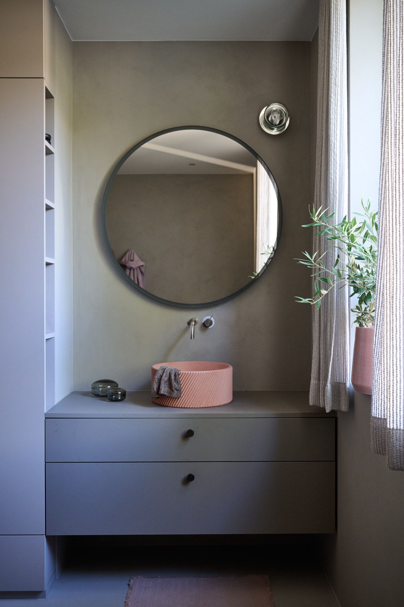 Modernes Bad-Design von Stephanie Thatenhorst mit rundem Spiegel, ikonischem Aufsatzwaschbecken und harmonischen Naturtönen.