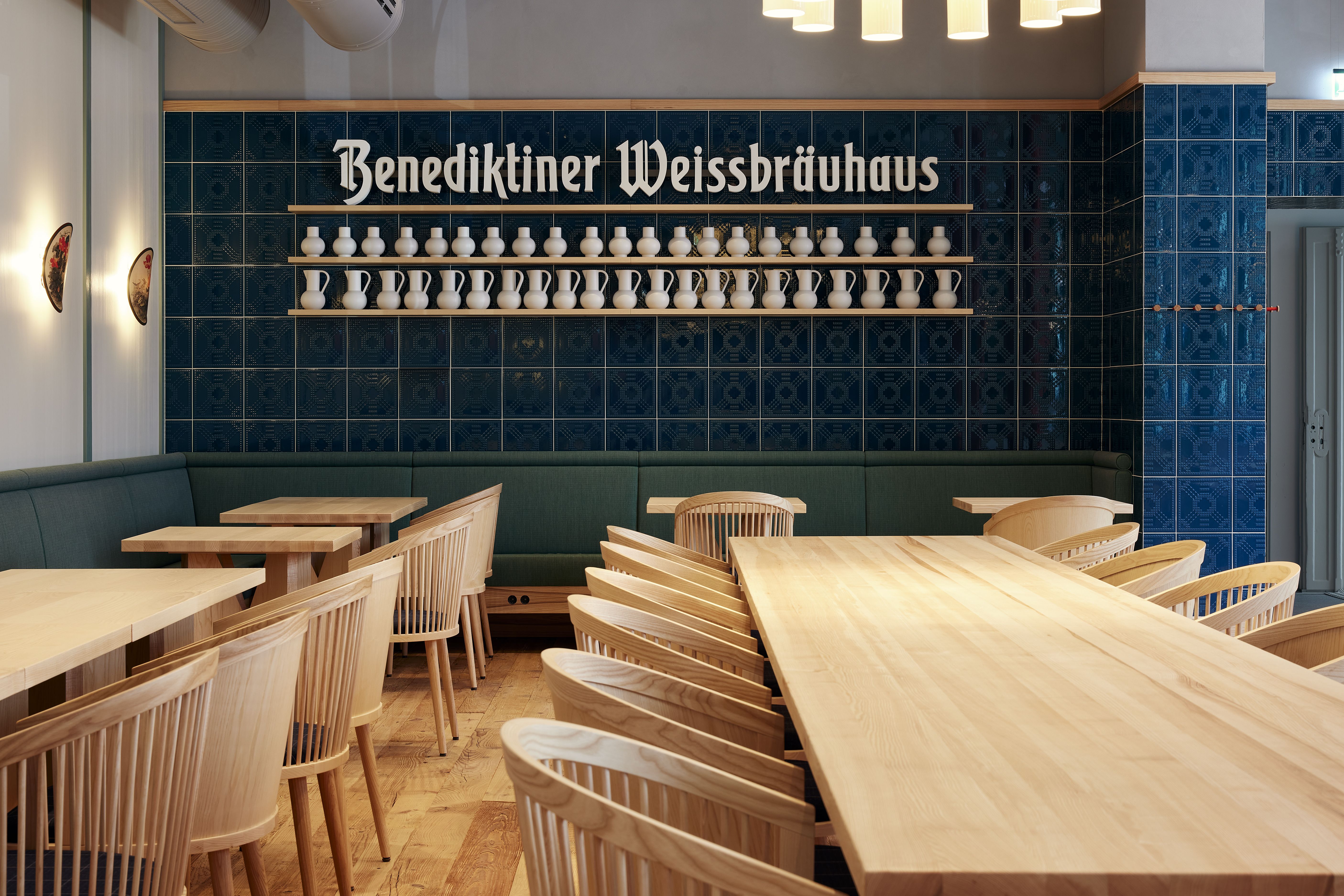 Die traditionelle Wirtshausatmosphäre des Benediktiner Weissbräuhaus zeigt sich in dunklen Kacheln, hellen Holztischen und einer modernen Interpretation bayerischer Gasthauskultur.
