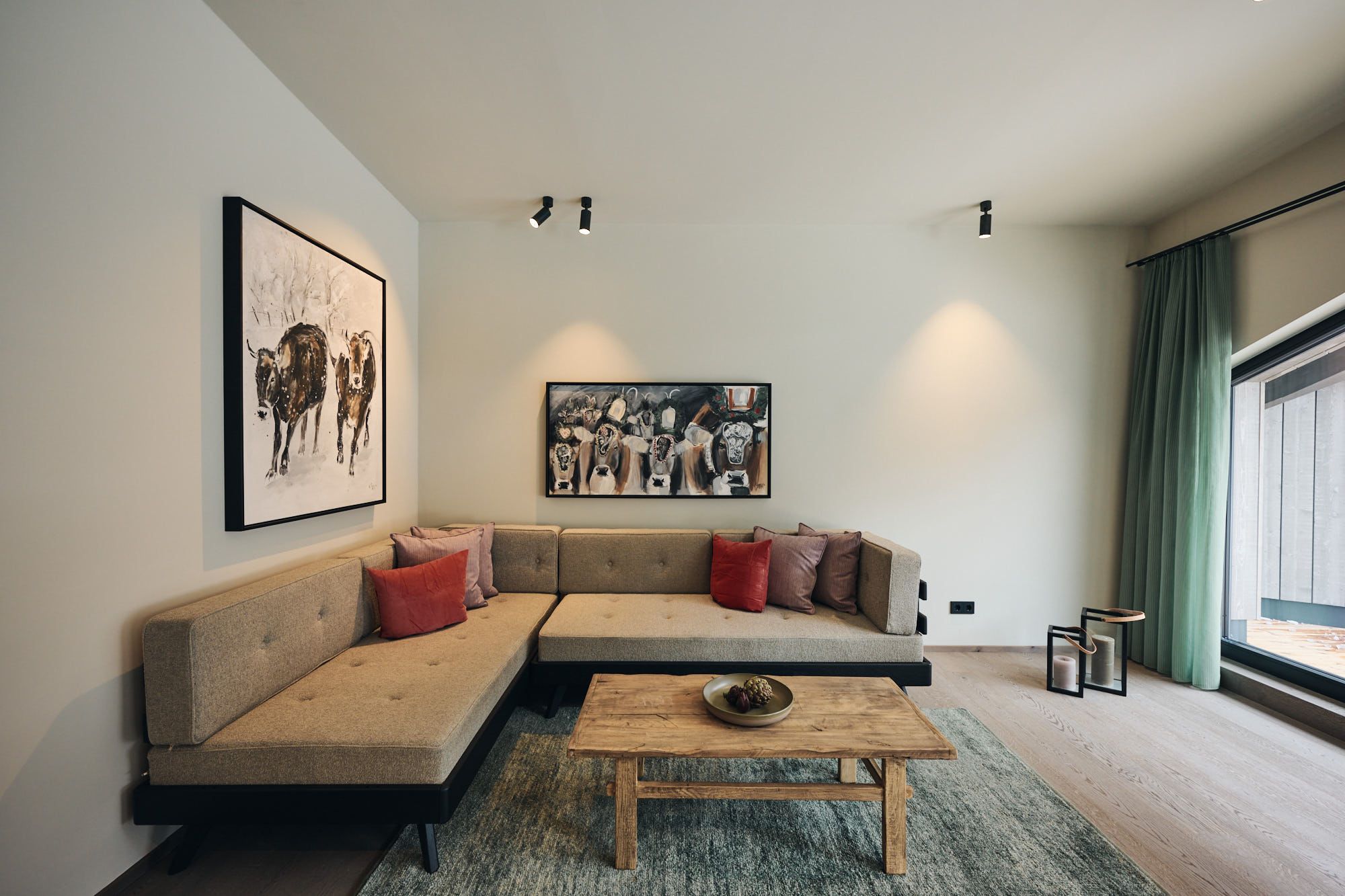 Das moderne Wohnzimmer im Ullrhaus – Hotel wurde von Stephanie Thatenhorst mit einer warmen Farbpalette und kunstvollen Kuhmotiven stilvoll inszeniert.