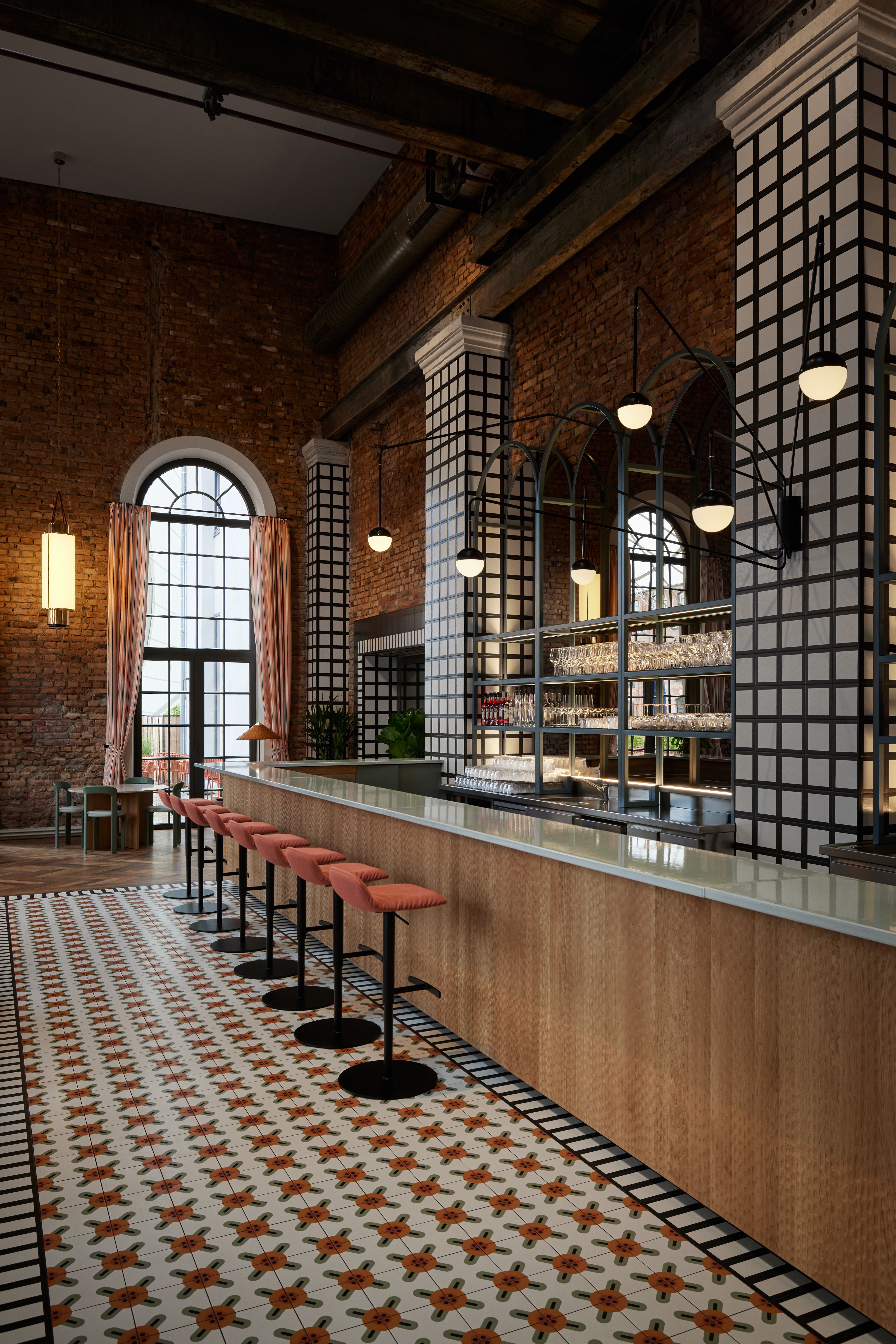 Die monochrom gerahmten Öffnungen, kontrastierenden Grid-Fliesen und Barfronten der Brasserie im Turbinenhaus Kolbermoor wurden von Stephanie Thatenhorst als grafische Raumordnung interpretiert.