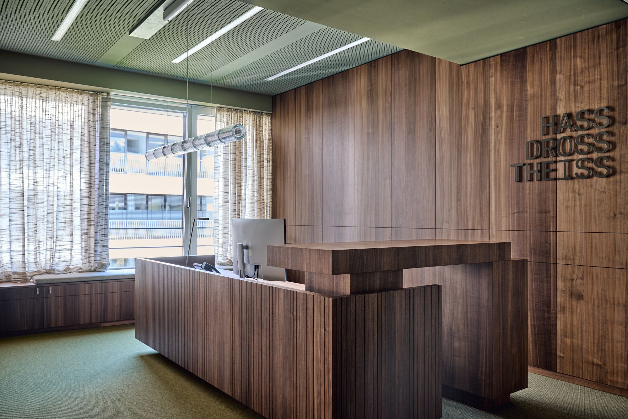 Im Büro Hass Dross Theiss inszeniert Stephanie Thatenhorst einen repräsentativen Empfangsbereich, in dem klare Linien, wertige Holzelemente und eine ruhige Farbgebung eine professionelle und zugleich warme Atmosphäre schaffen.