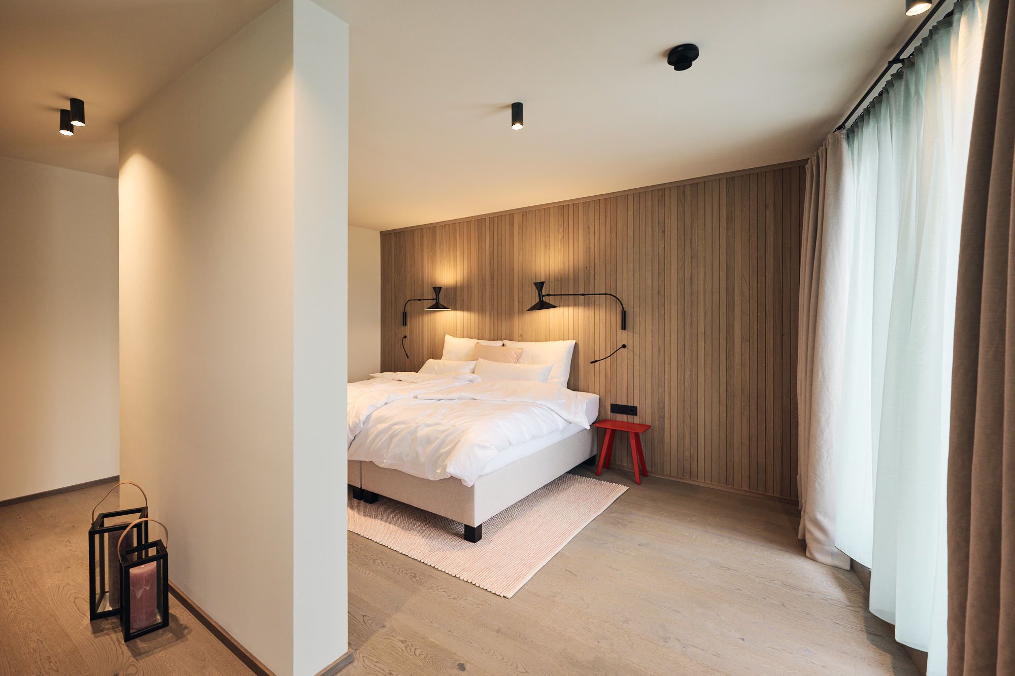 Das von Stephanie Thatenhorst gestaltete Schlafzimmer im Ullrhaus Hotel verbindet natürliche Holzvertäfelung mit moderner Lichtgestaltung zu einer ruhigen Wohlfühlatmosphäre.